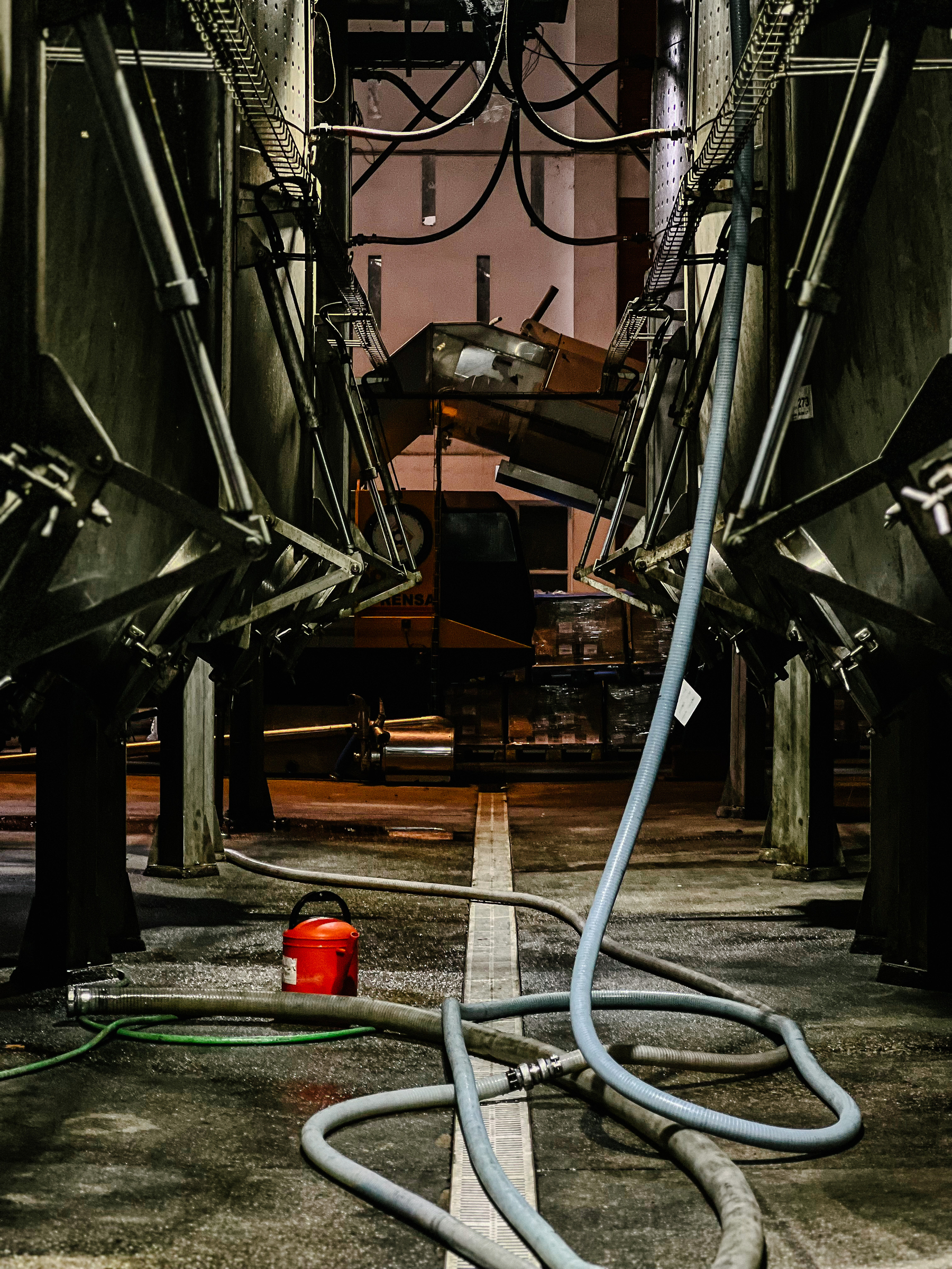 Inside of a winery, with metal and hoses all over the place. 