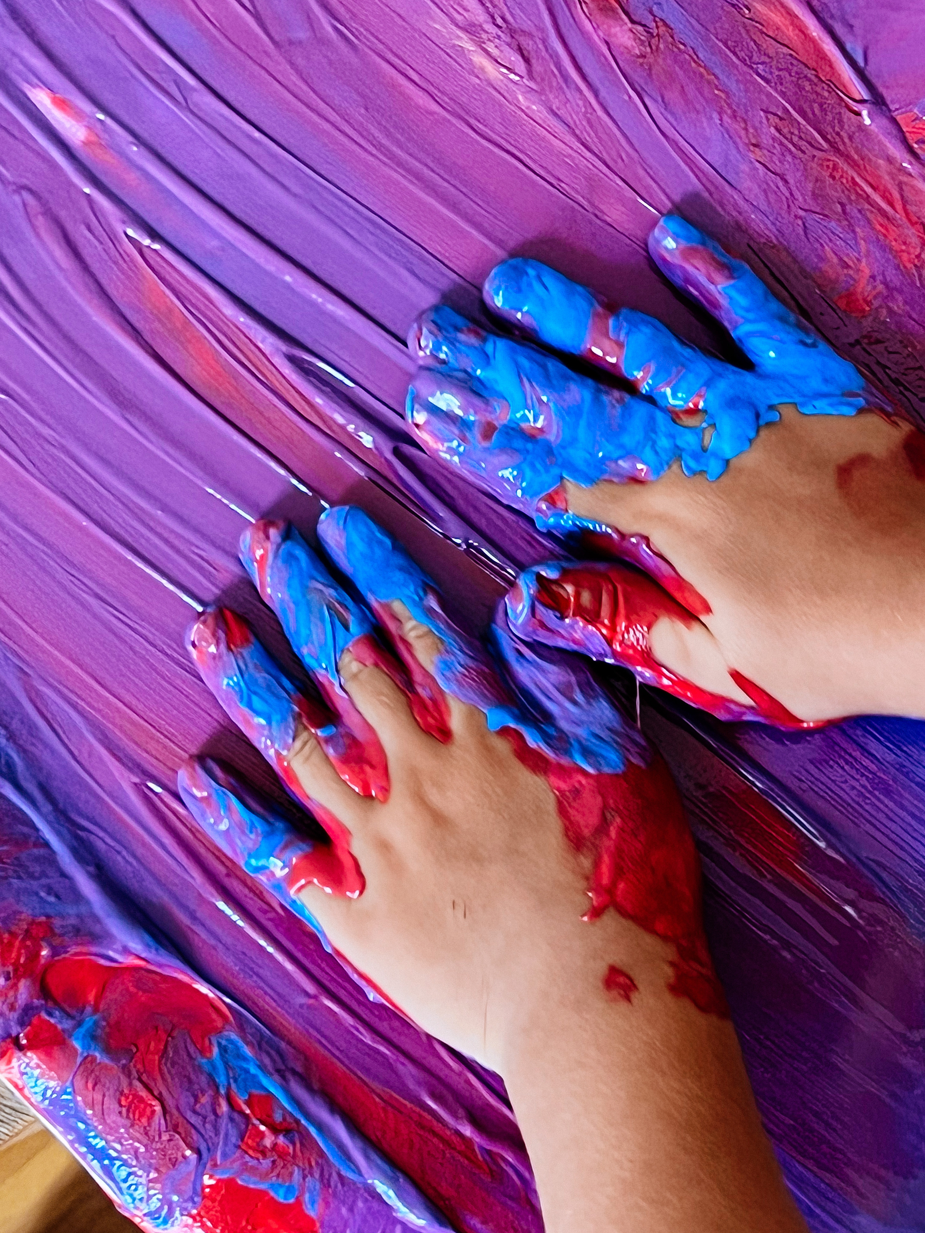 toddler hands spread paint over paper