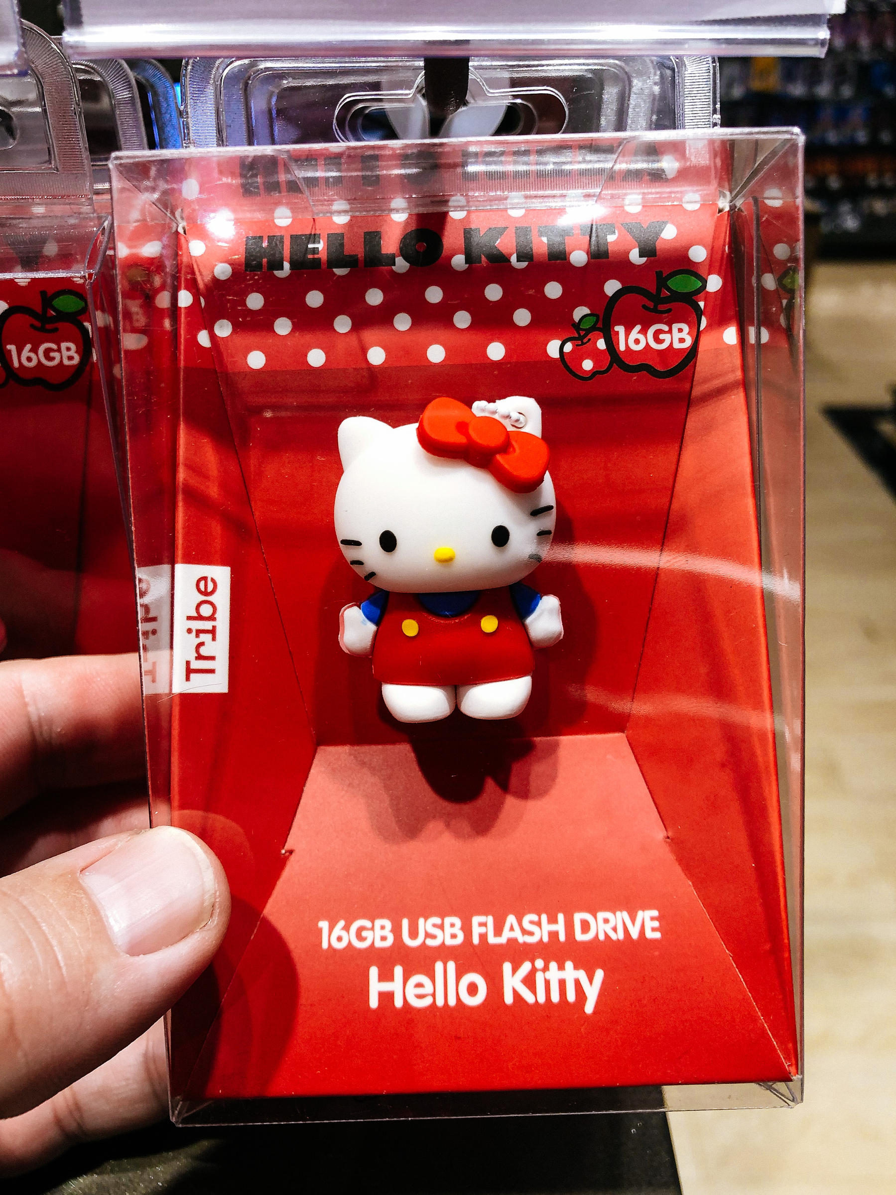 A hand holds an Hello Kitty shaped USB thumb drive in a box. 