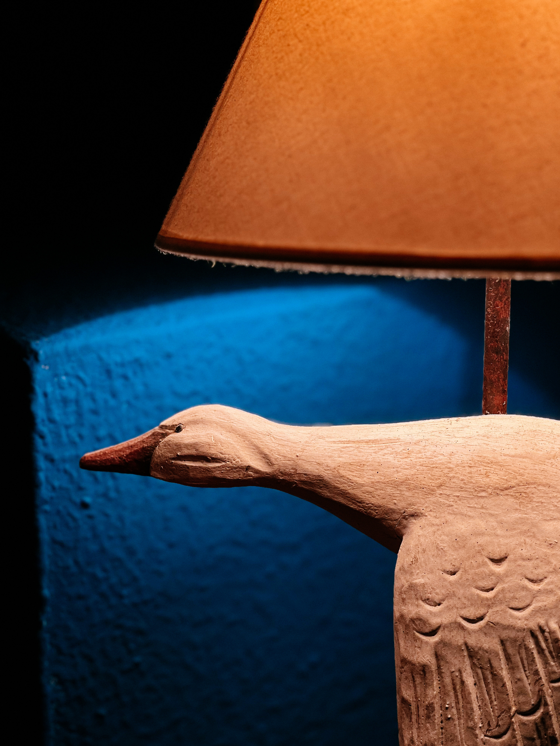a white wooden duck, a lamp, and a blue wall