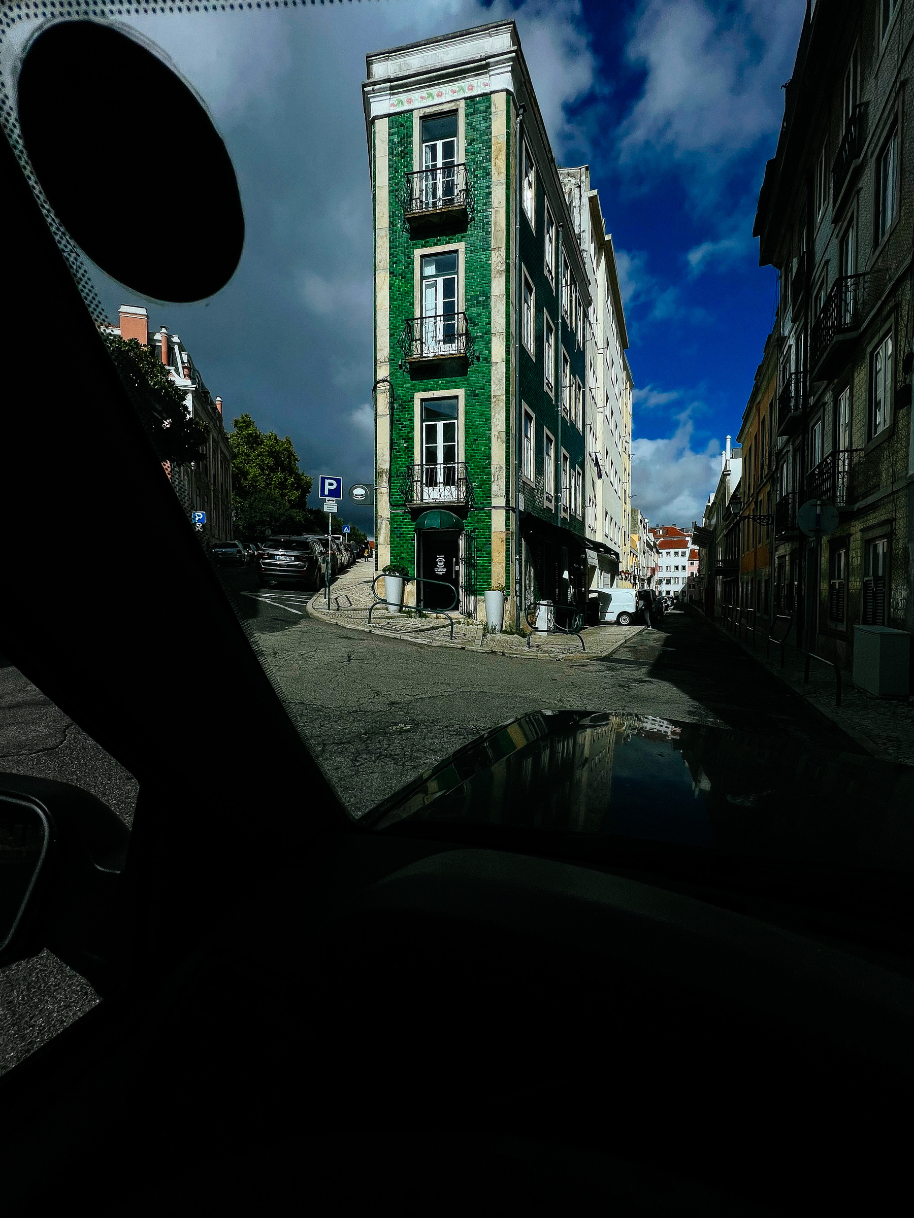 view from inside a car, a green skinny building in the middle of the city