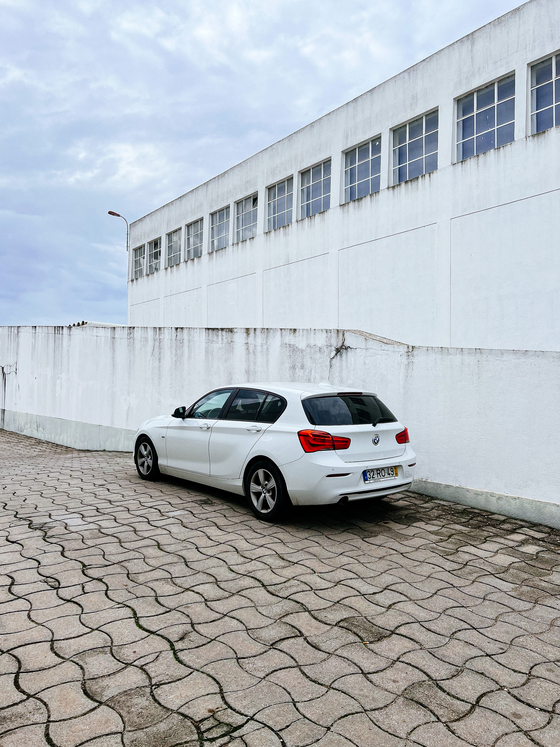 A white car, with a white ramp, and a white building on the background 