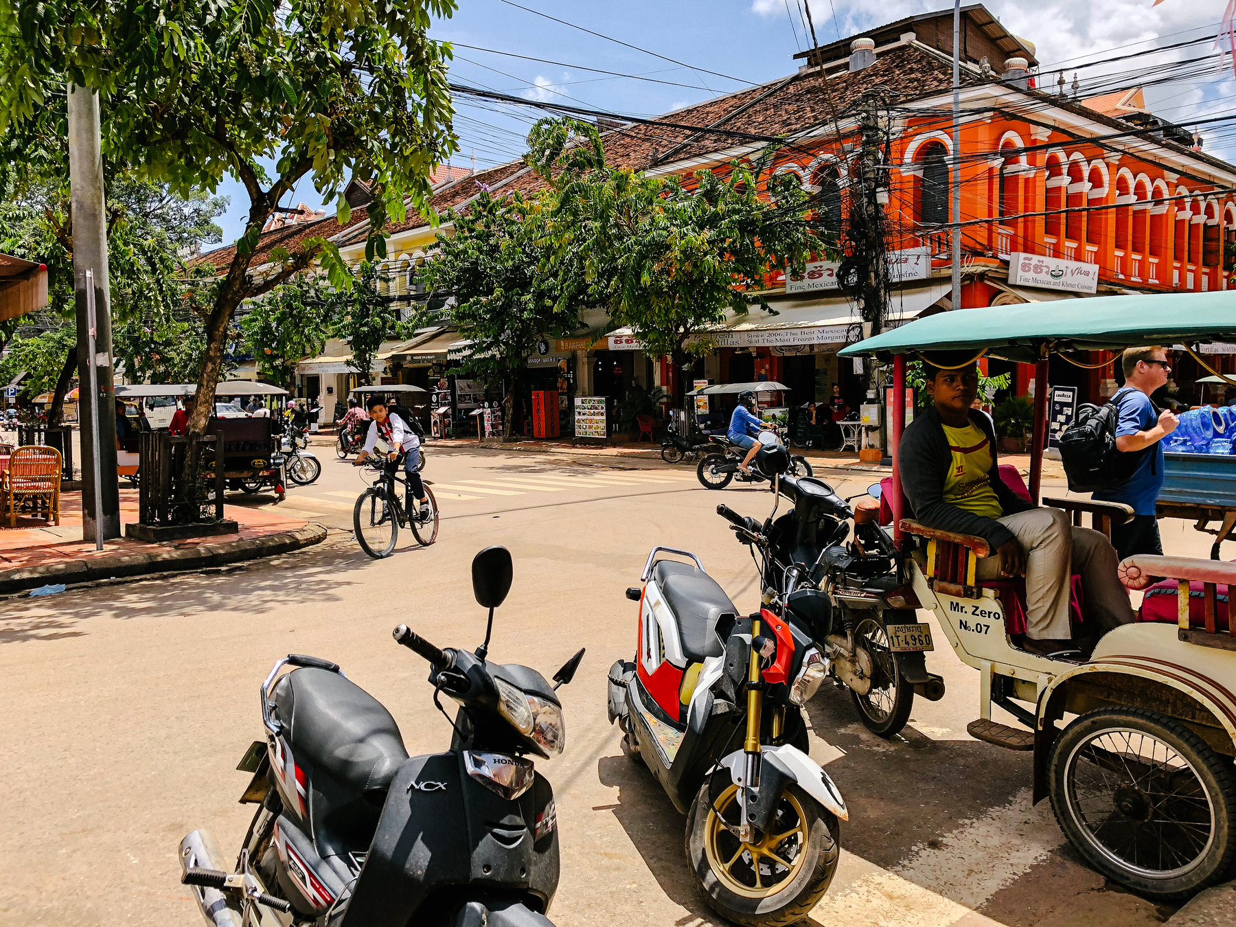 city scene, tuk tuk, bicycles, and people going about