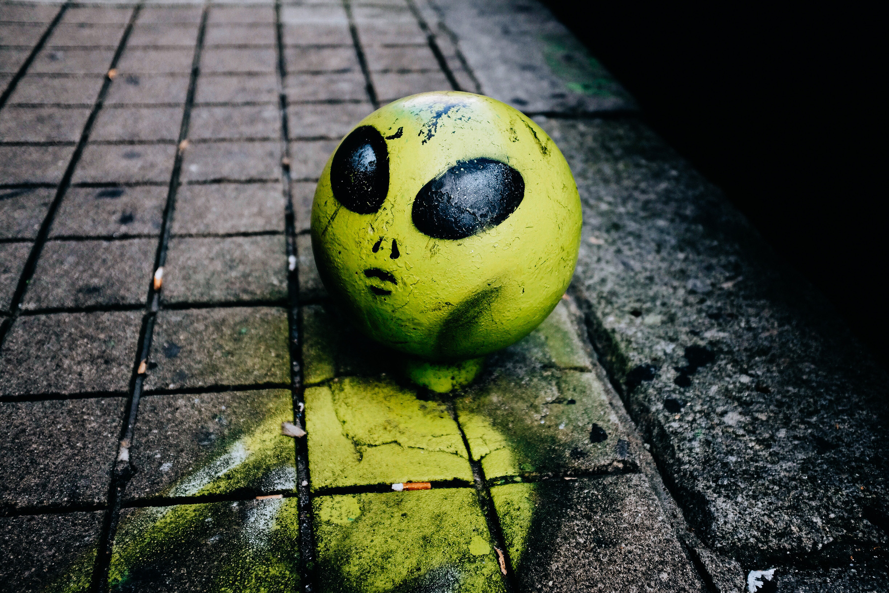 Urban furniture can turn into something surreal. Someone painted a steel ball on the sidewalk into an alien’s head, and added a body. 