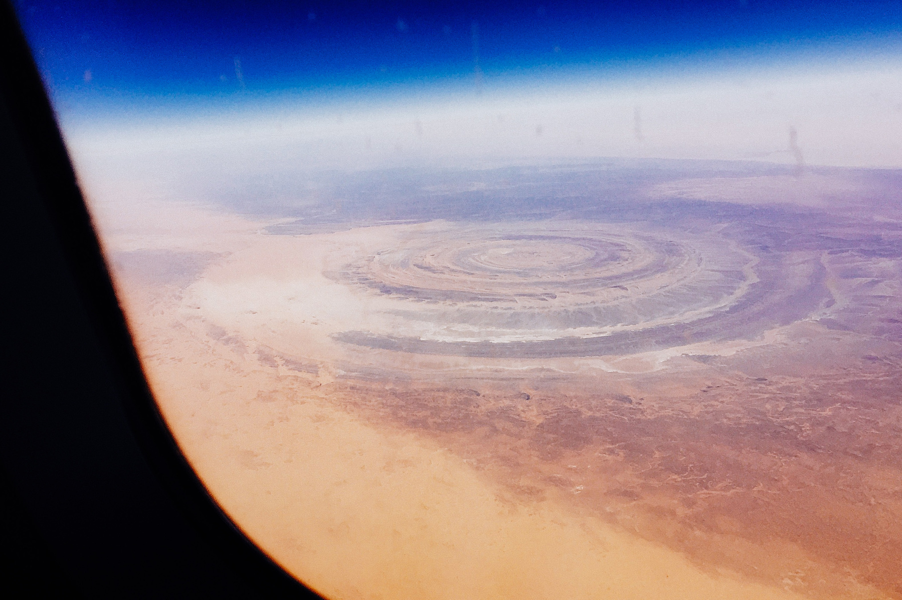 Photo taken from an airplane, shows a circular pattern in the middle of the desert.