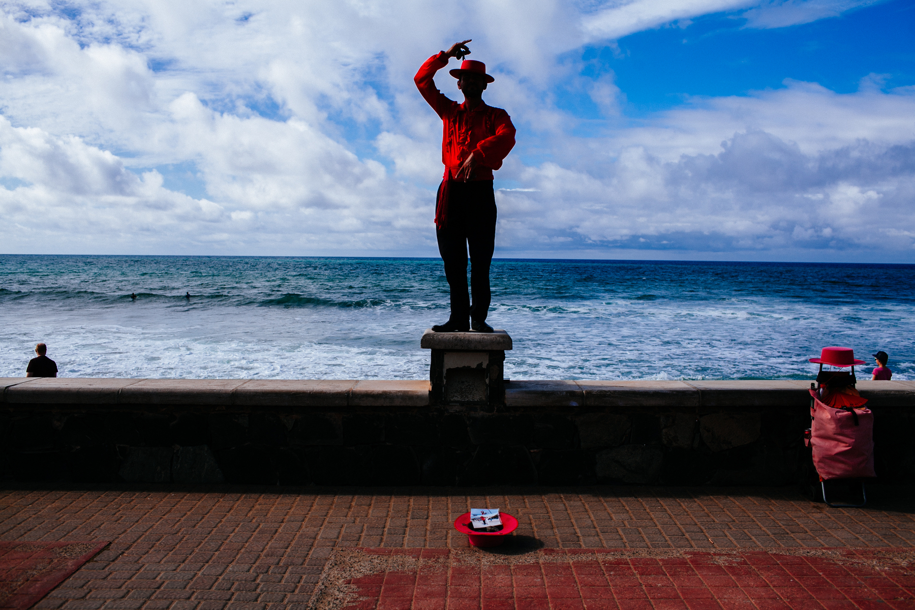 A “human statue” performer stands still in front of the ocean. 