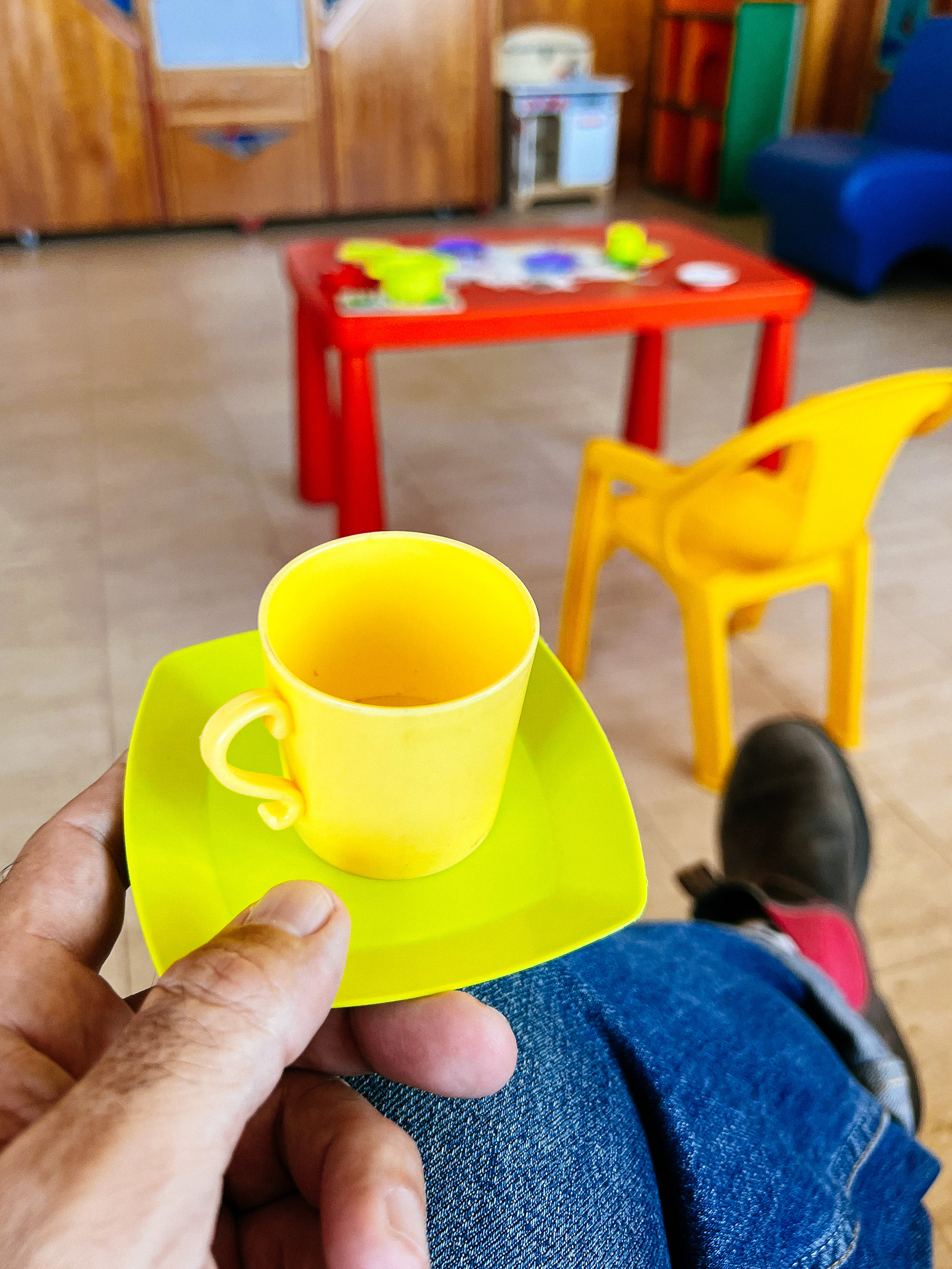 a plastic coffee cup, with plastic furniture in the back