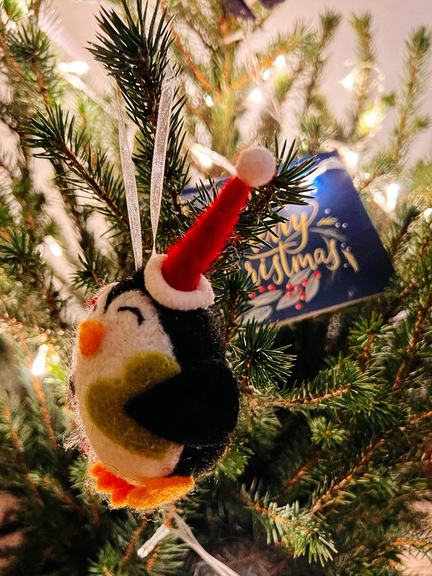 A Christmas ornament, a penguin, hanging on the xMas tree. 