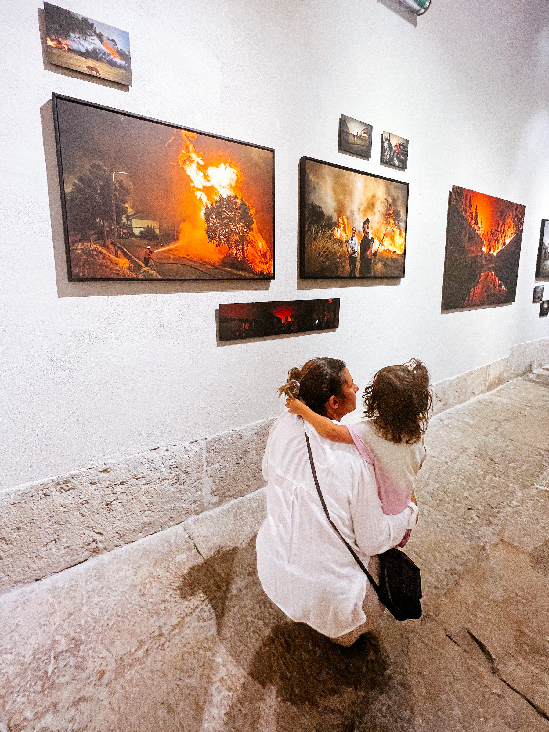a mom and a toddler look at photos on a wall