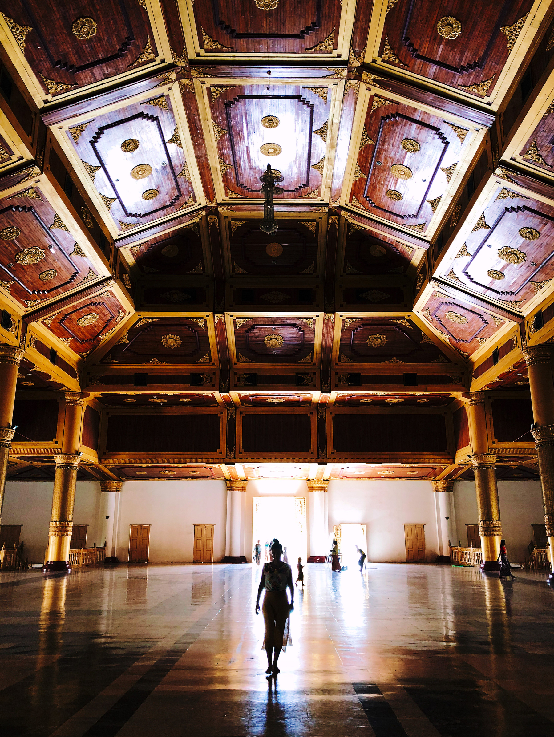 a woman walks toward us inside a huge temple room