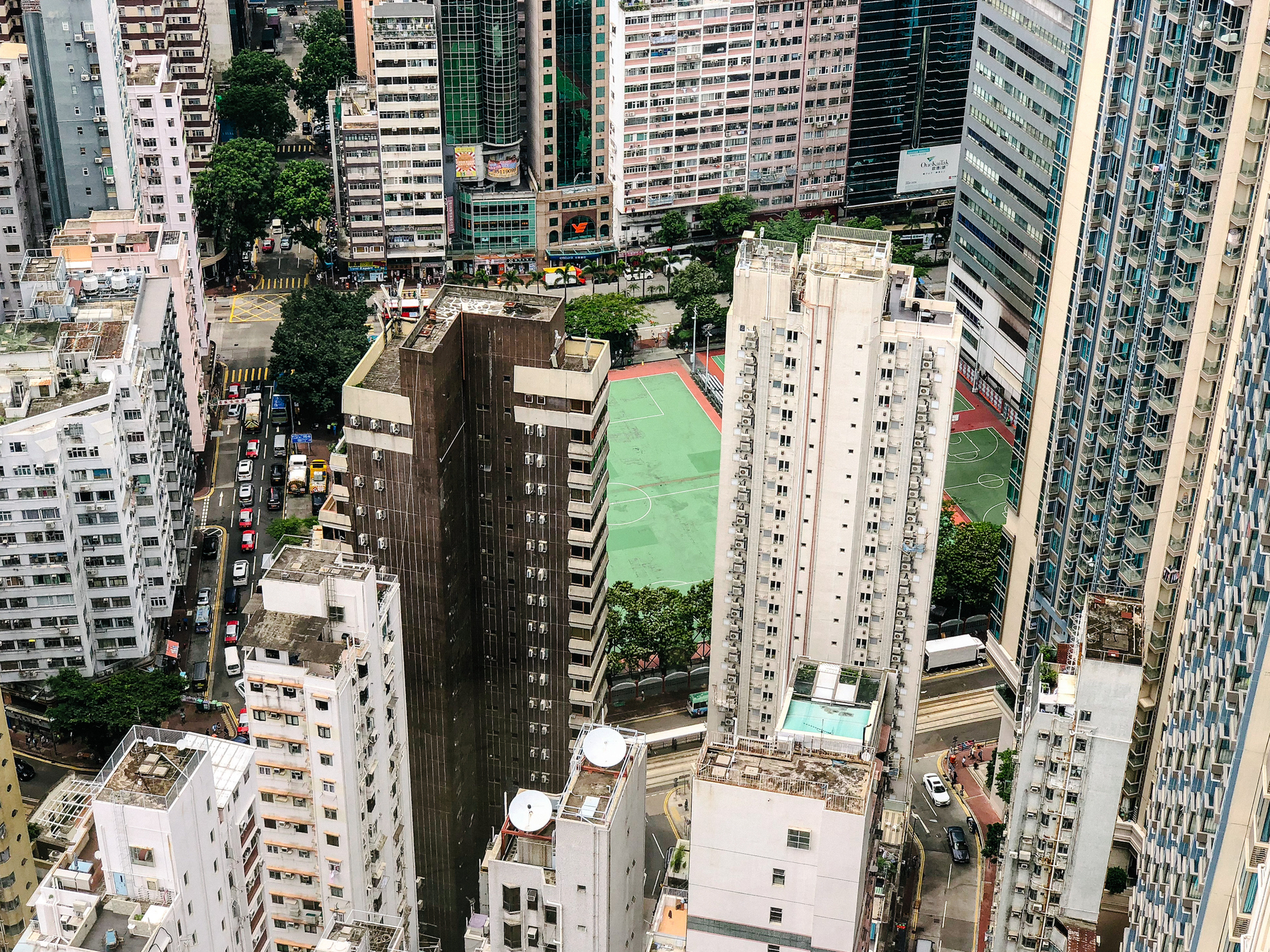 looking down from the top of a tall building, you can see a football pitch in the middle of the huge city mess