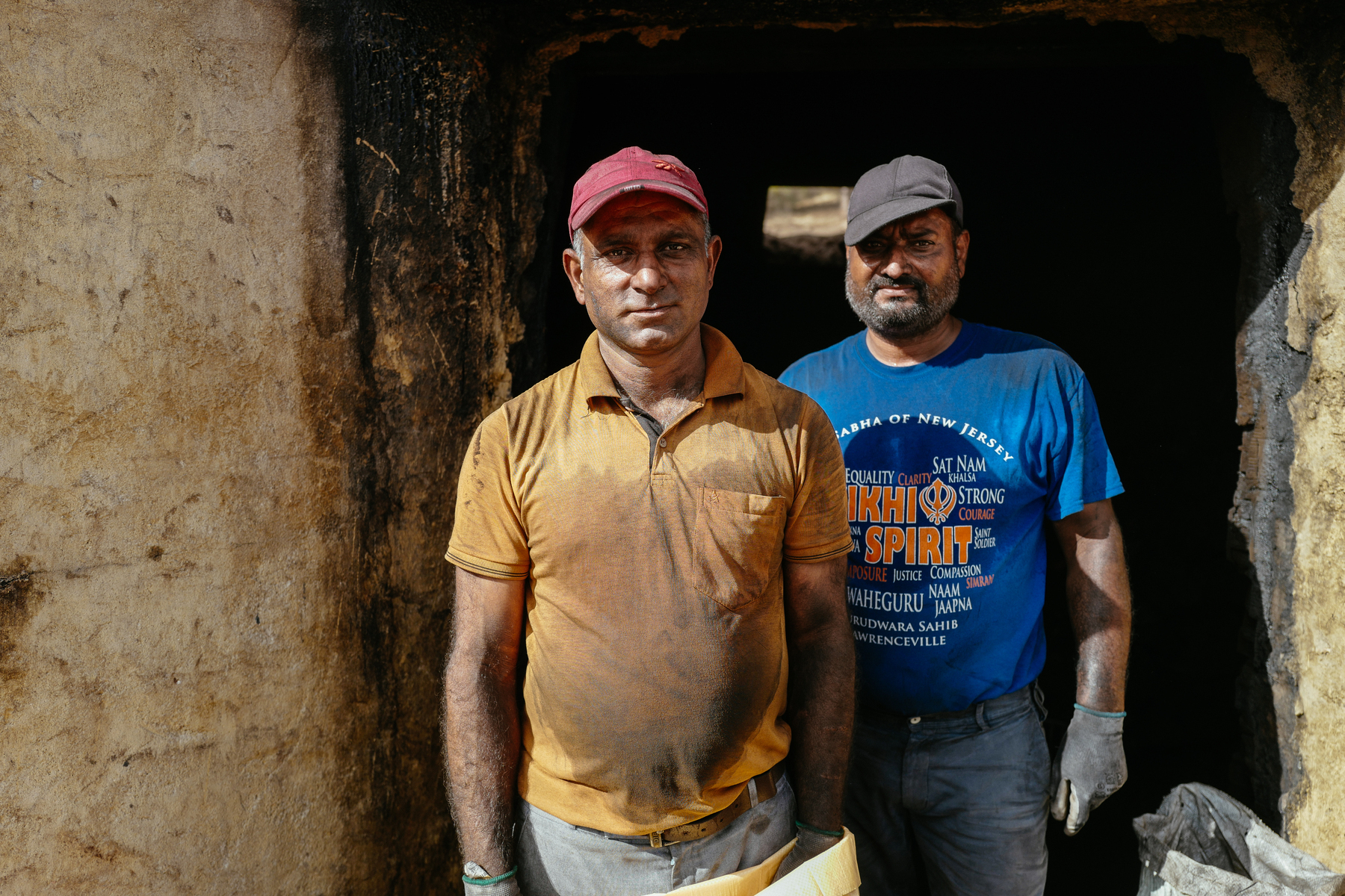 two workers from a charcoal factory, faces dirty with coal dust