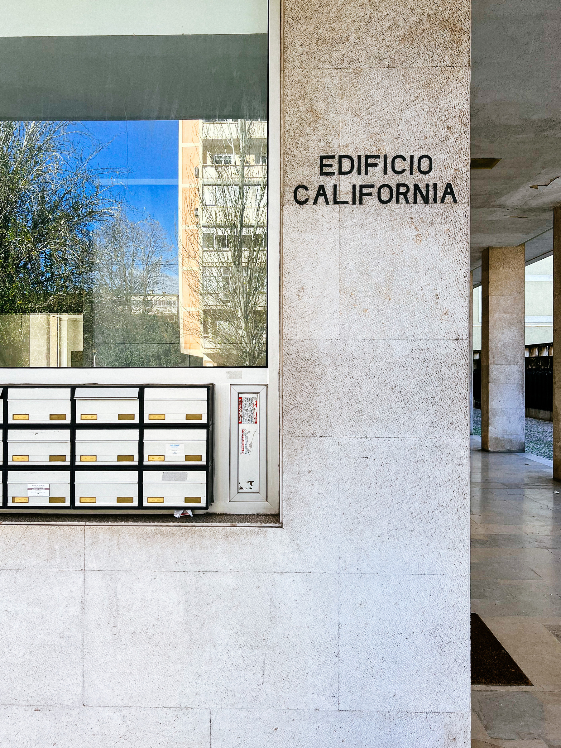 Entrance to a building, with some mailboxes, and a sign that says “Edifício Califórni”, California Building in Portuguese. 