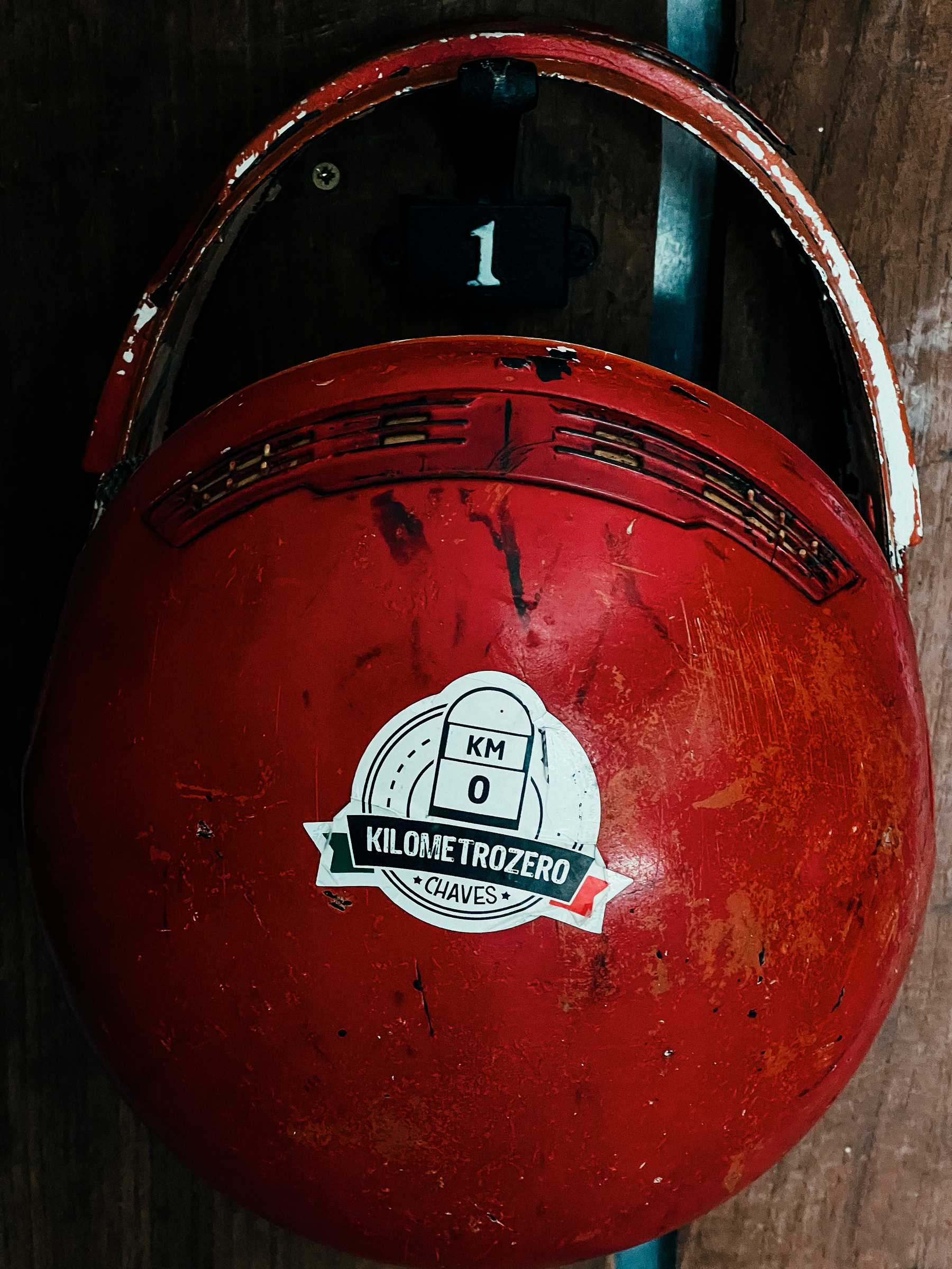 A red motorcycle helmet with a sticker on it. 
