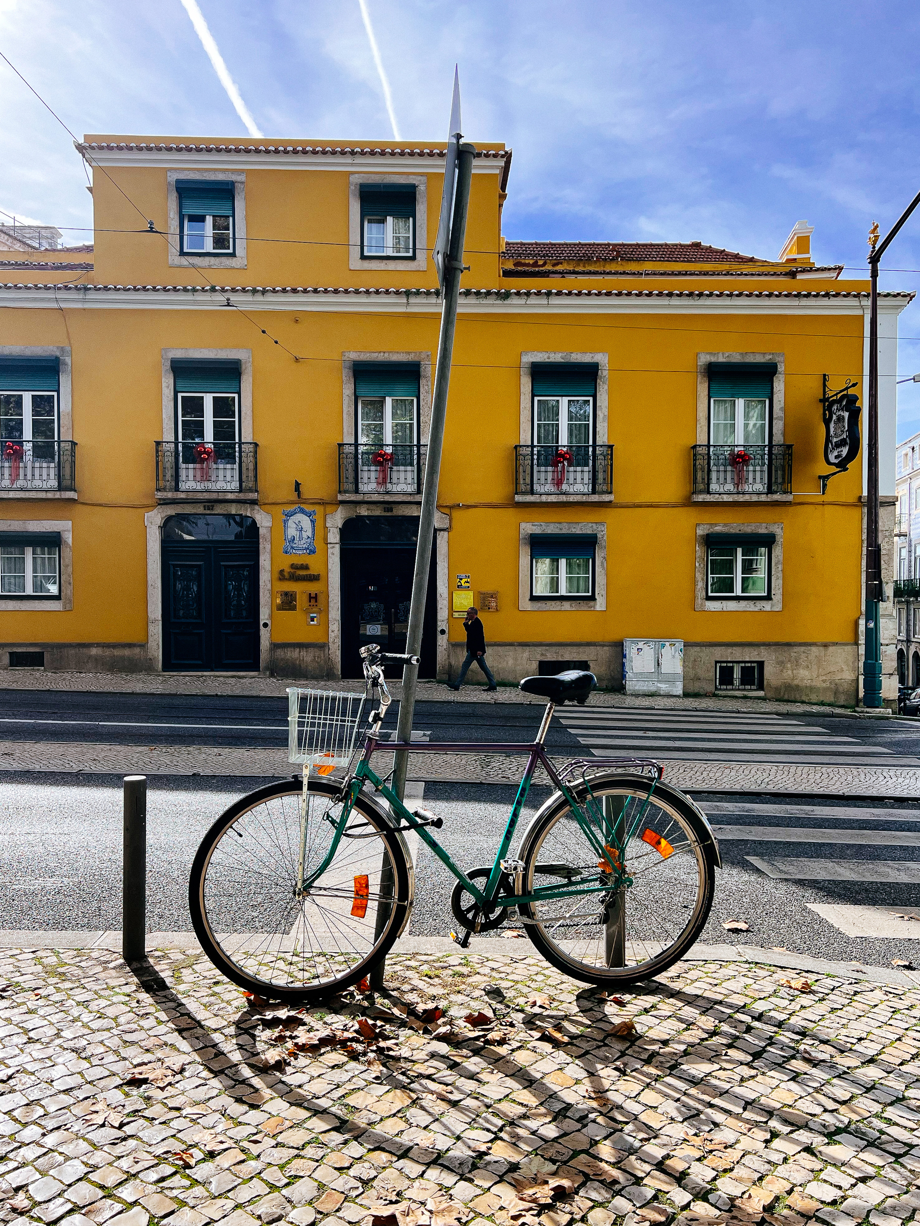 A parked bicycle, with a yellow building in the background. 