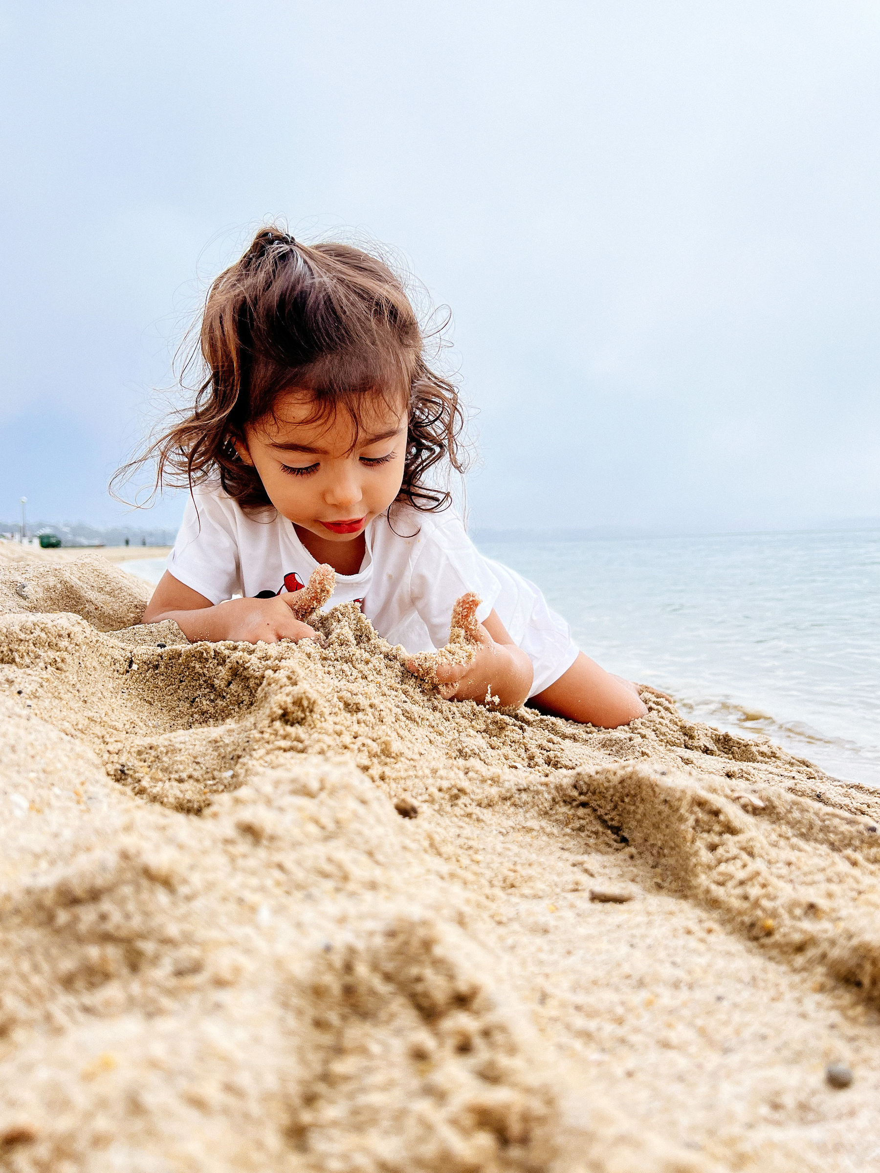 Toddler by the sea, playing with sand
