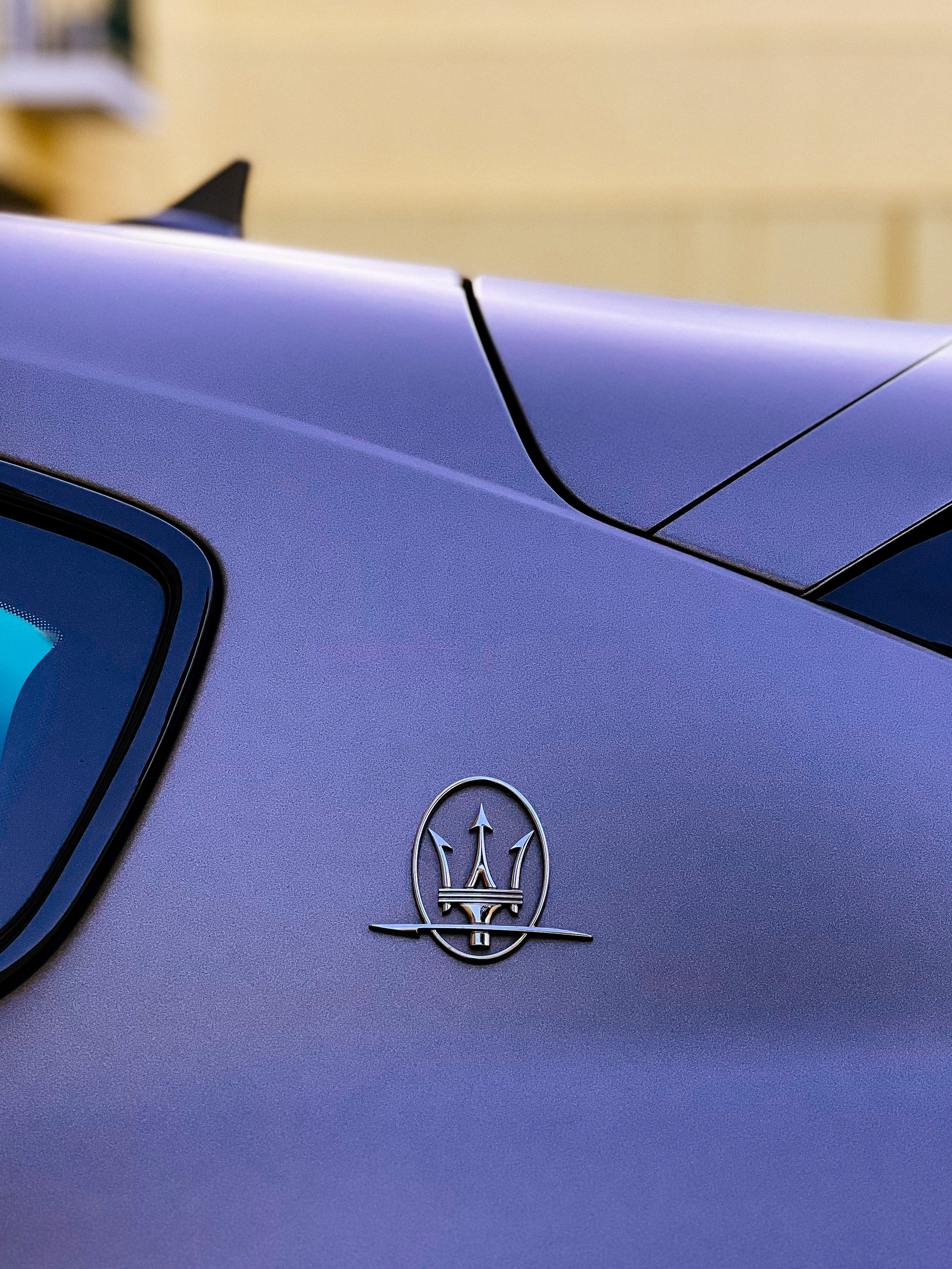 Detail of a Maserati logo on the side of a car.