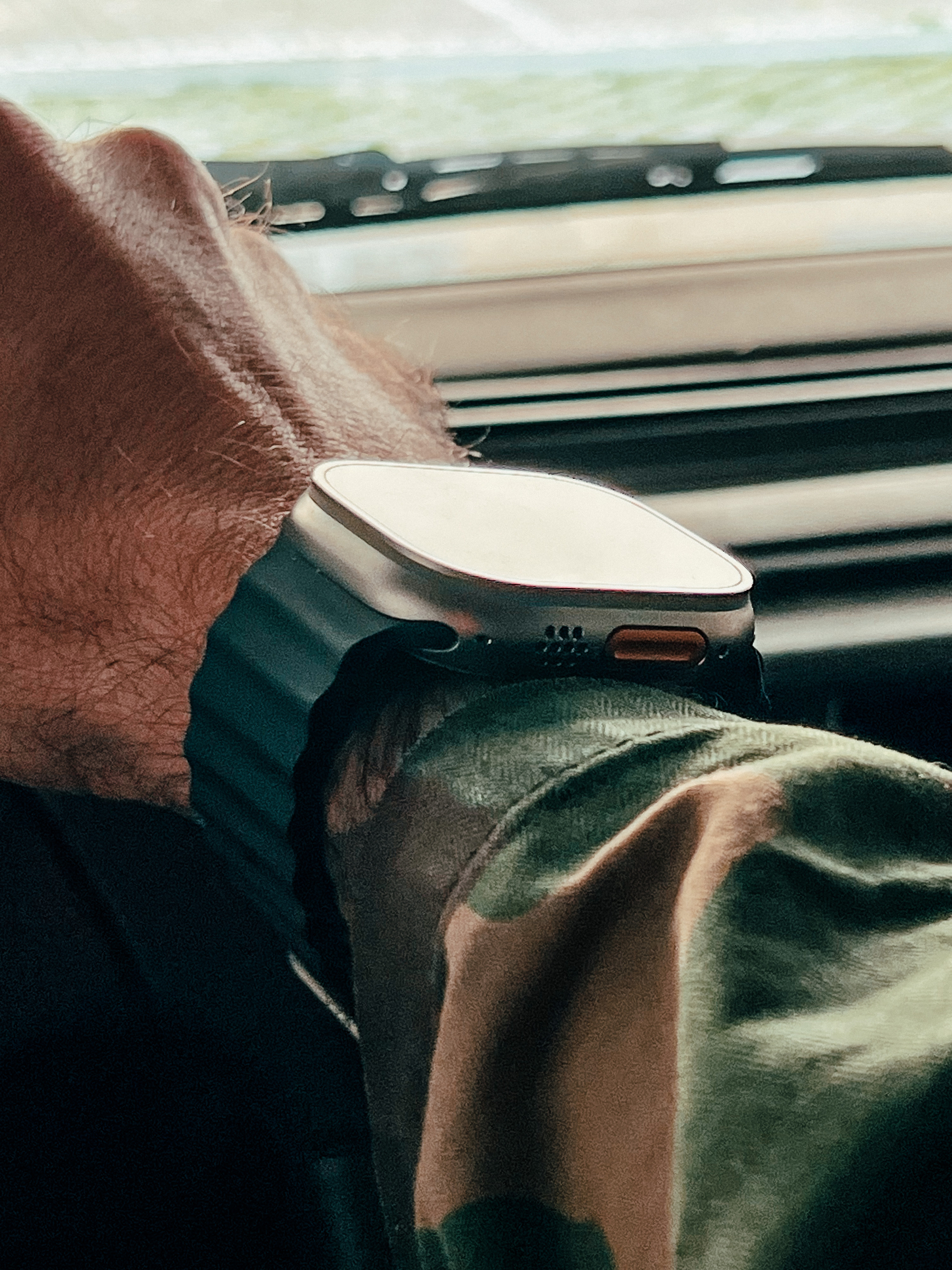 An Apple Watch Ultra on a wrist, we can see a camouflaged jacket covering the arm