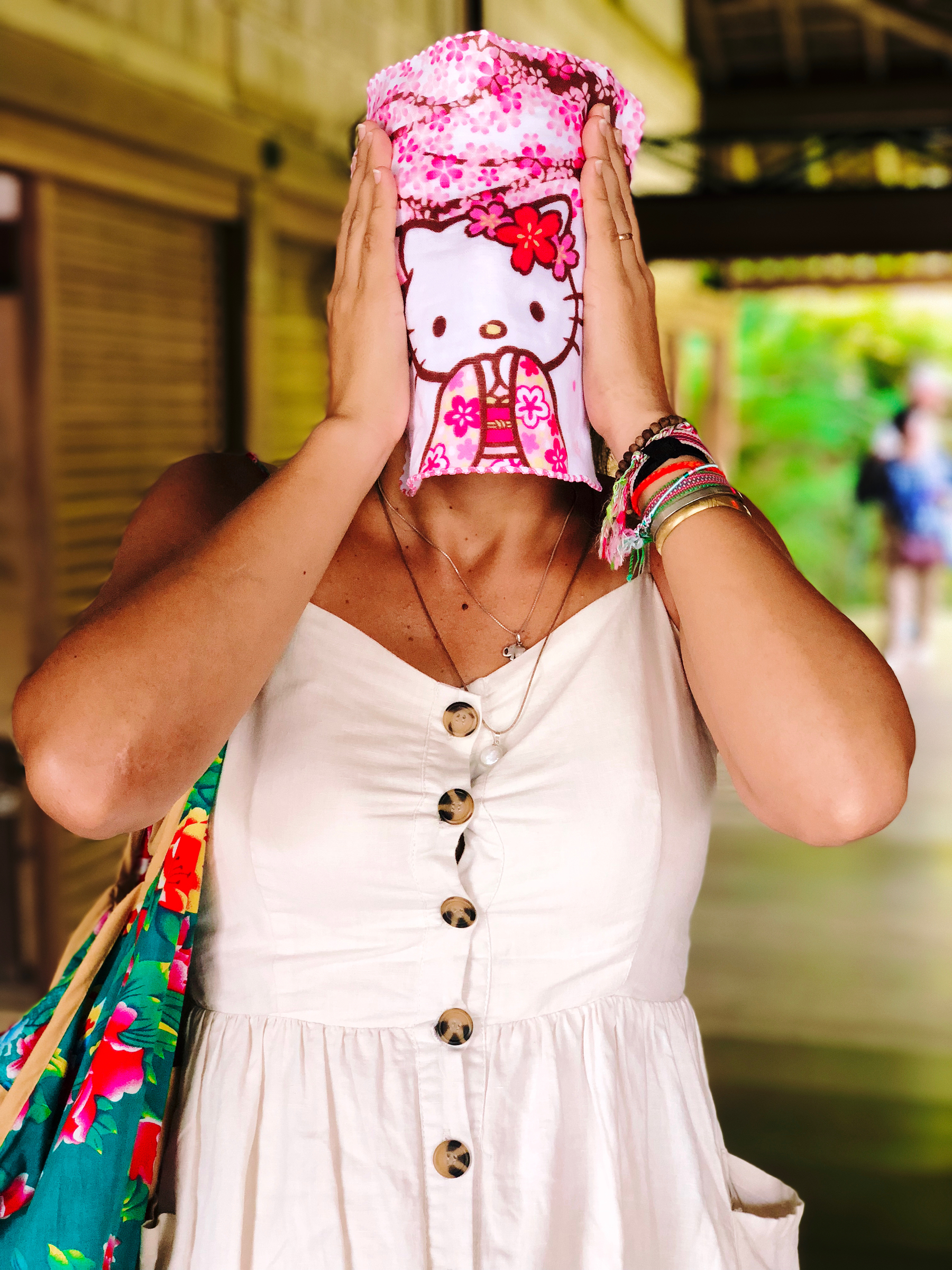 A woman covering her face with a small Hello Kitty towel. 