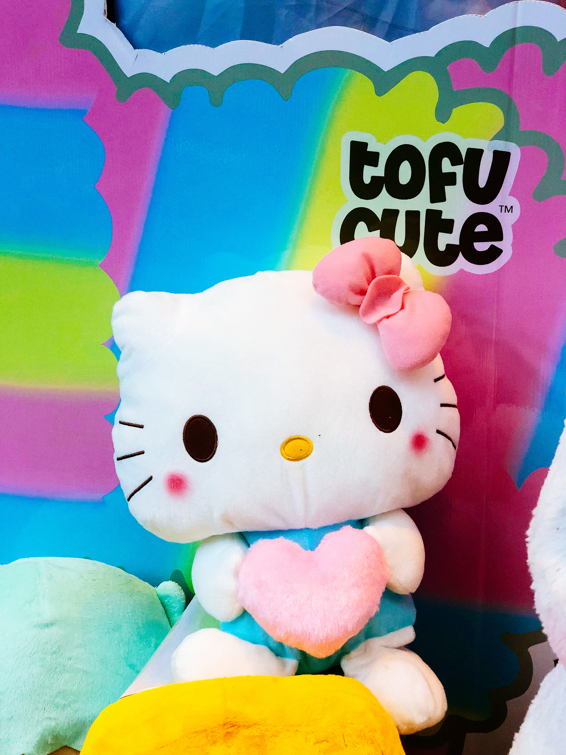 Hello Kitty plush toy, holding a heart. The words “Tofu Cute” behind her. 