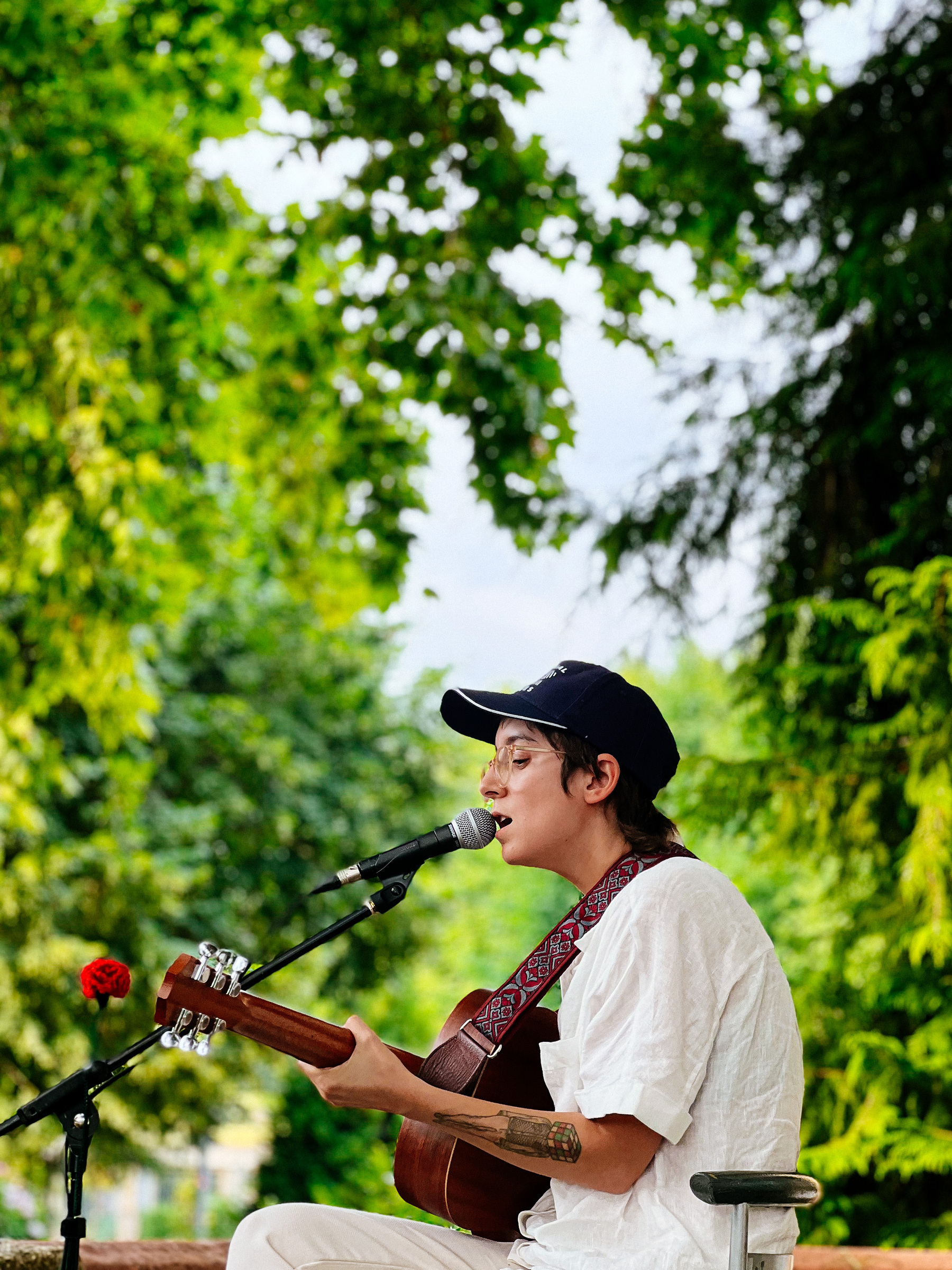 A musician plays guitar in the garden. 