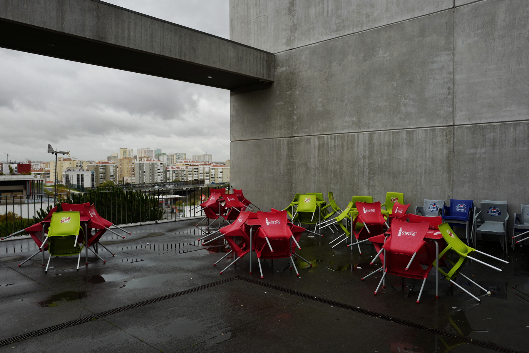Groups of colorful chairs next to a concrete building. 