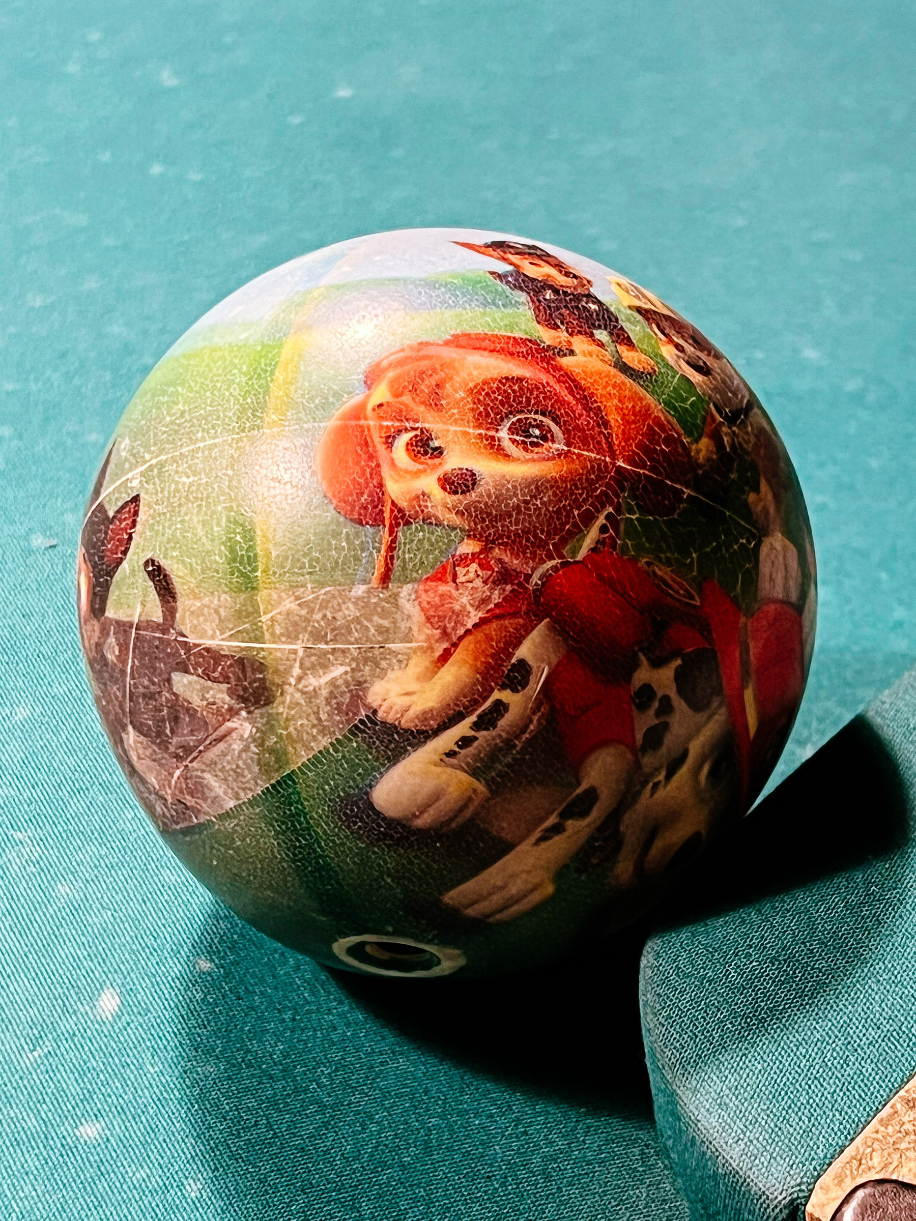 A ball with Skye from the Paw Patrol on a pool table. 