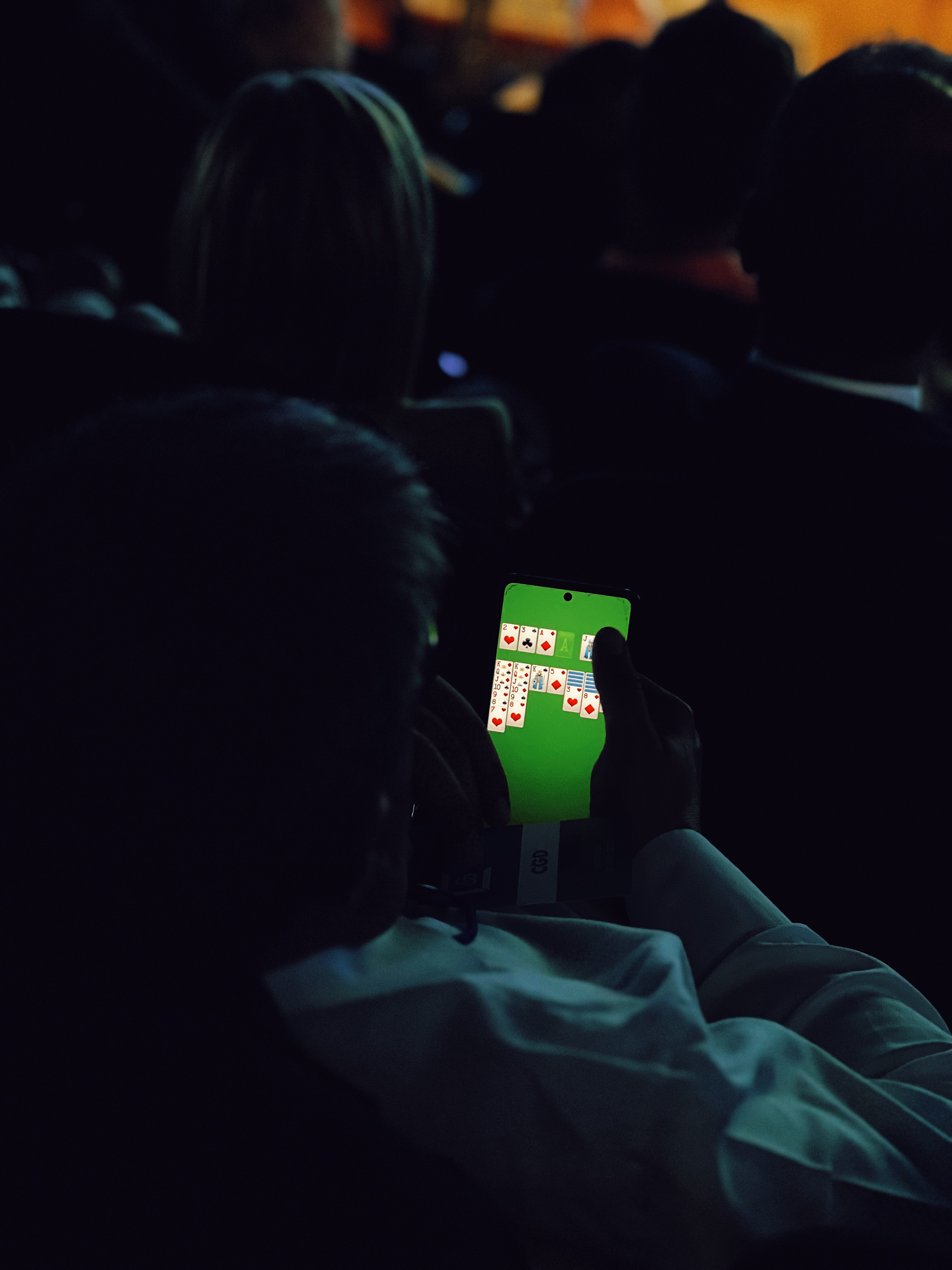 A man plays Solitaire on his phone, while attending a conference. 
