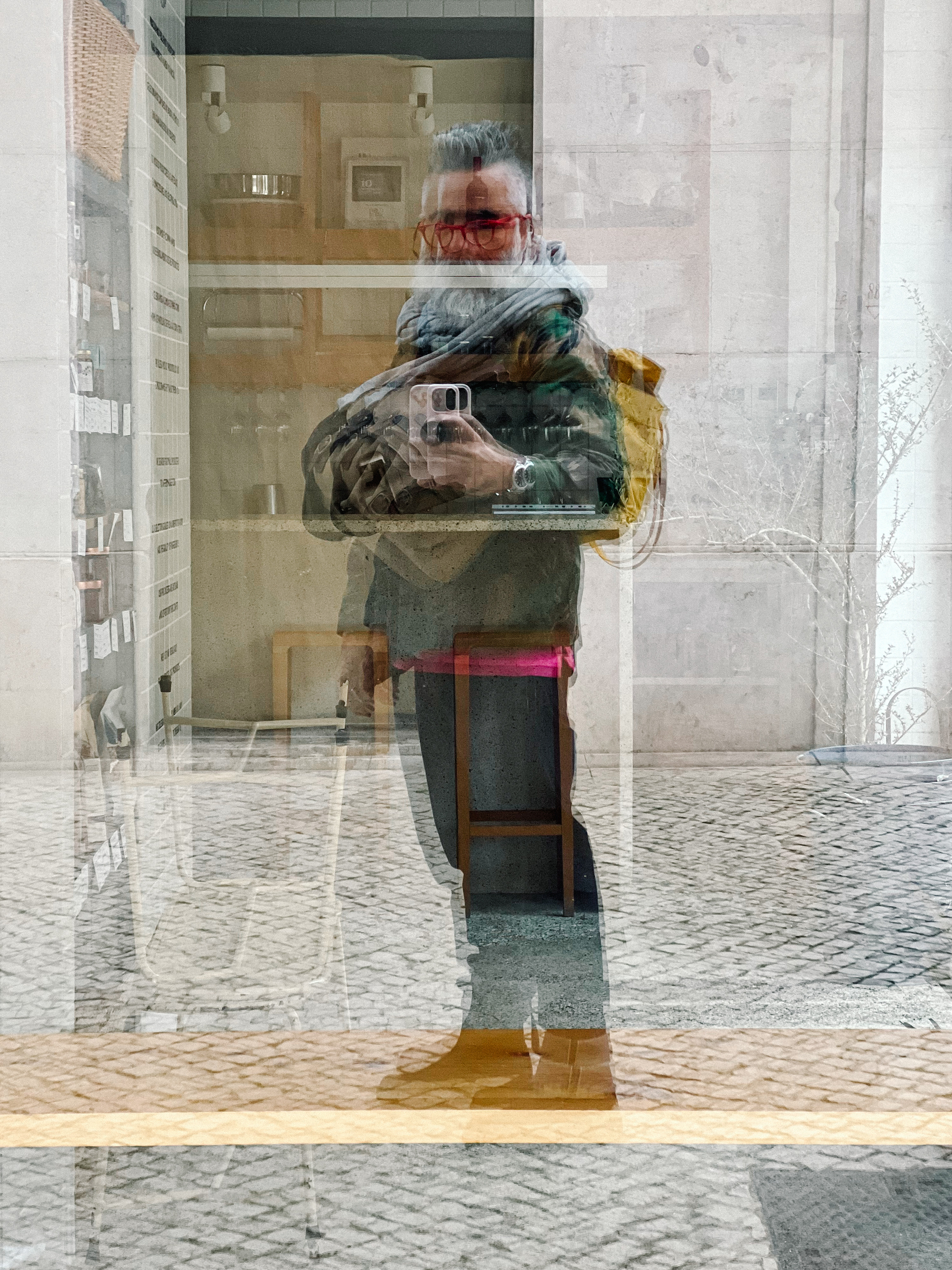 Self portrait, reflected on a shop window. Backpack on the back, camera bag in front. 