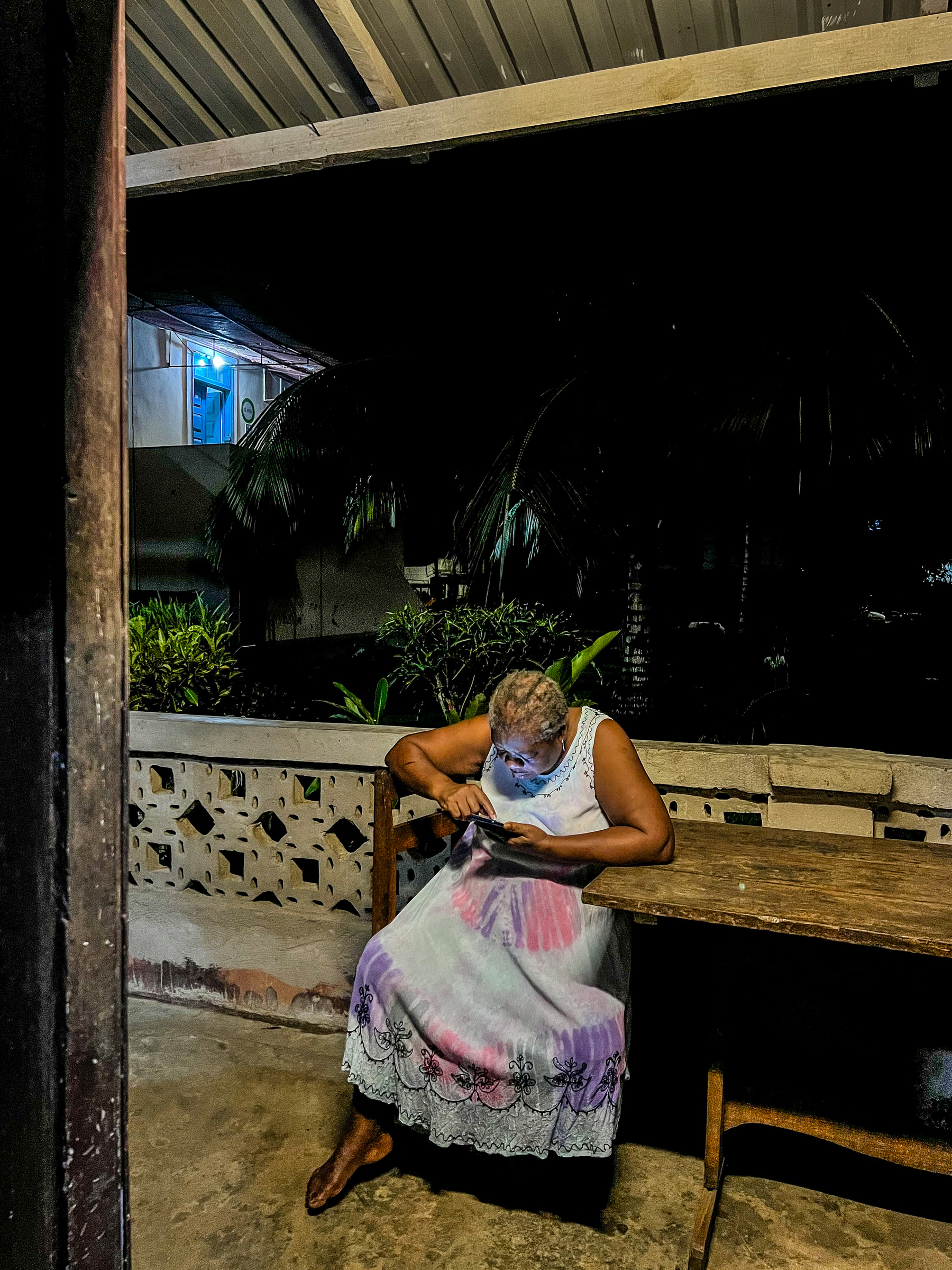 A woman sits looking at her phone. 
