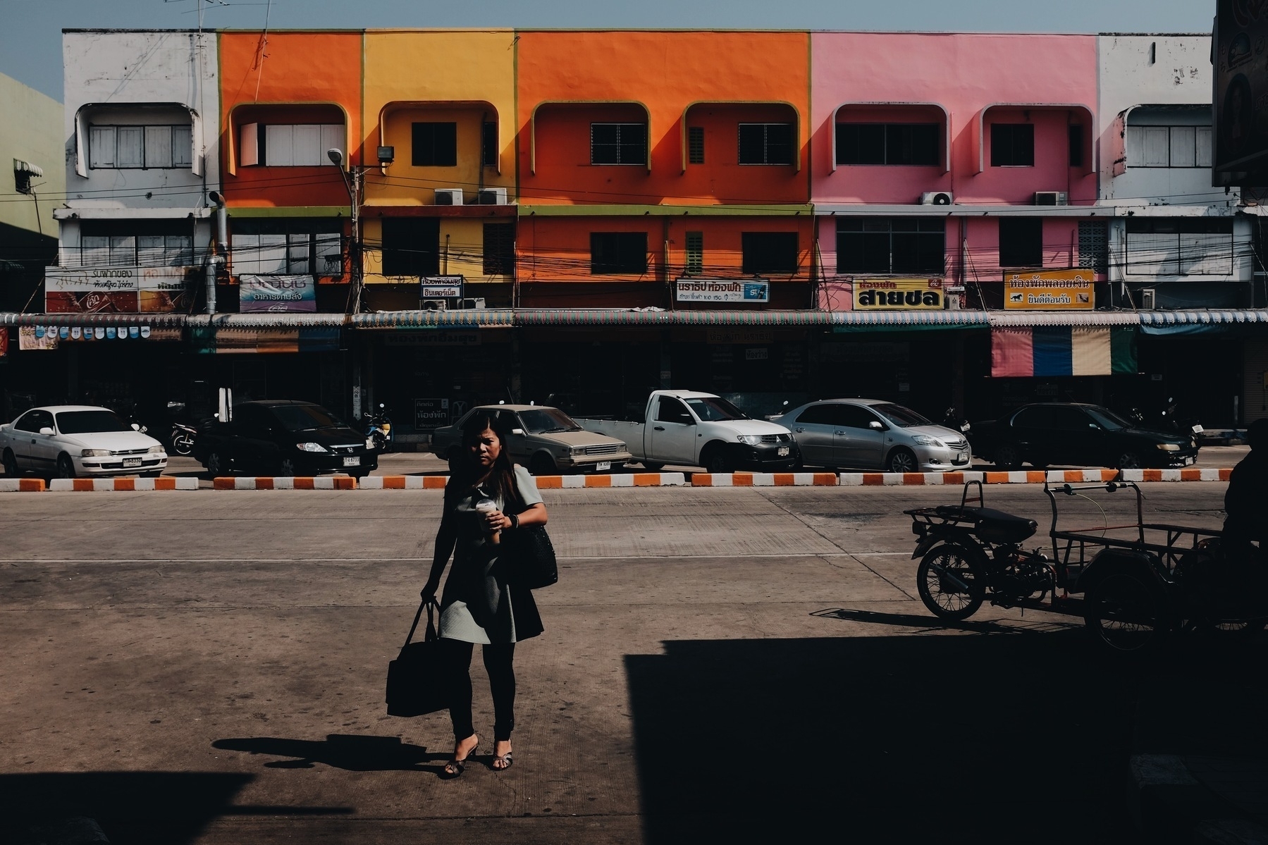 a lonely woman walks towards us, colorful buildings in the back