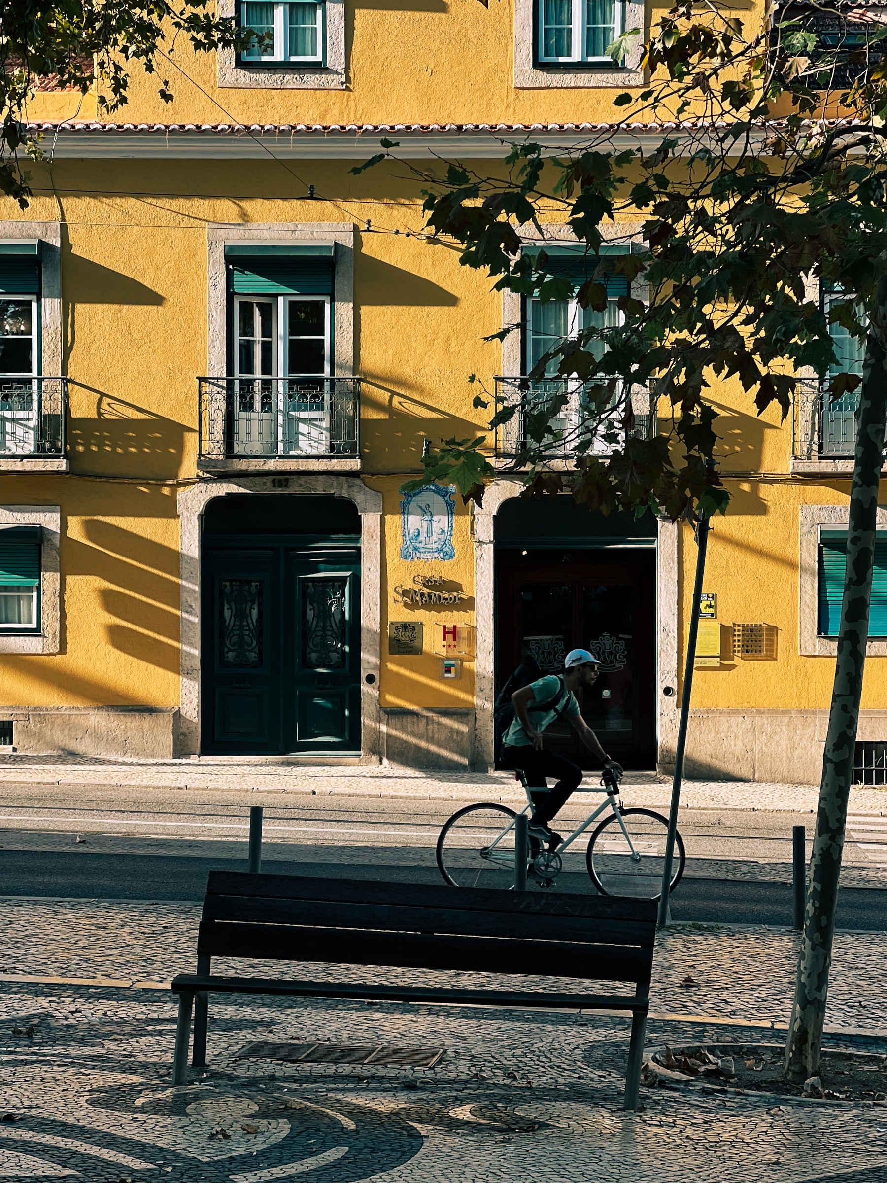 A cyclist rides by a lovely yellow building.