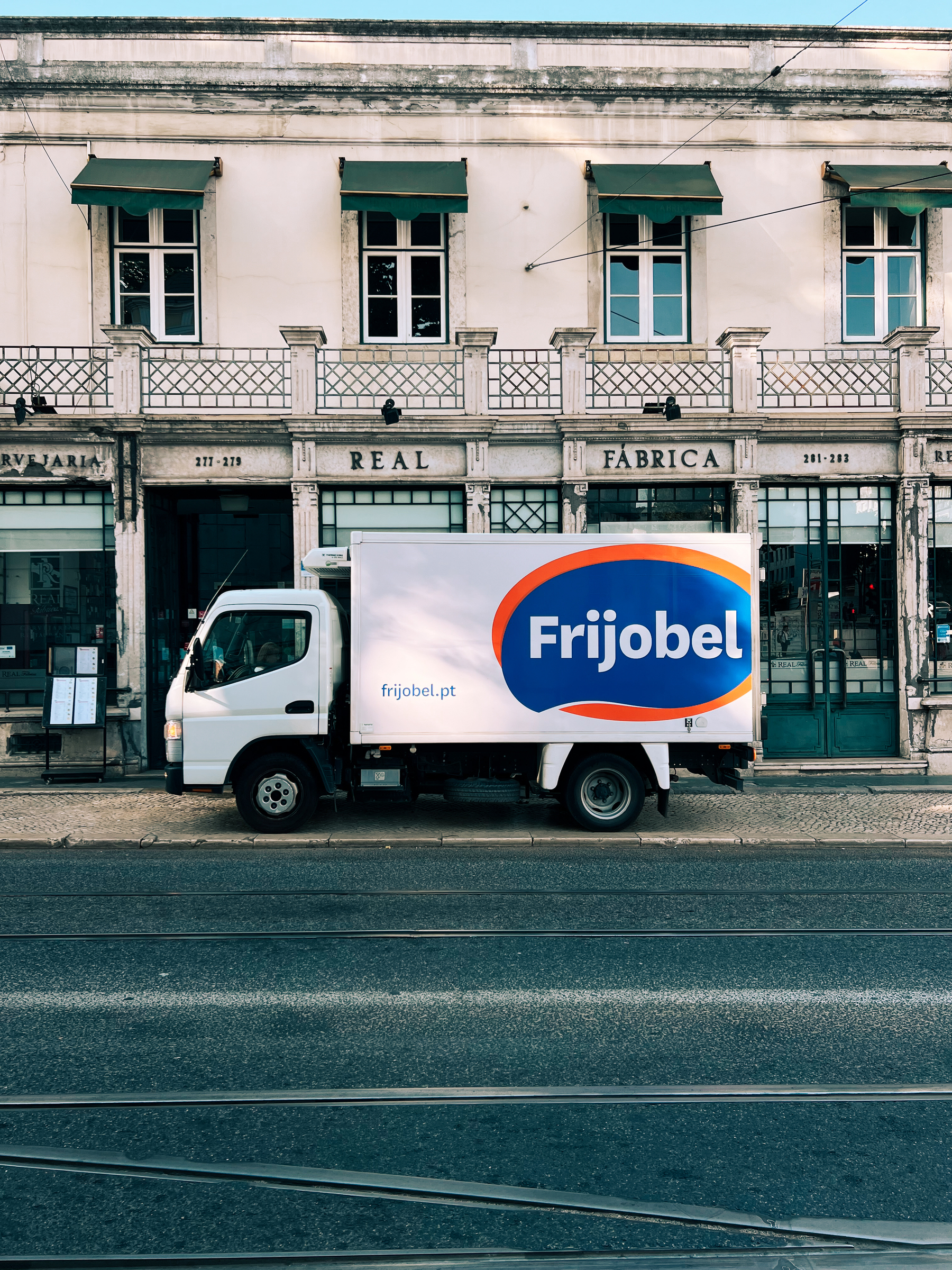 A Frijobel truck parked in front of a restaurant. On the sidewalk, of course.