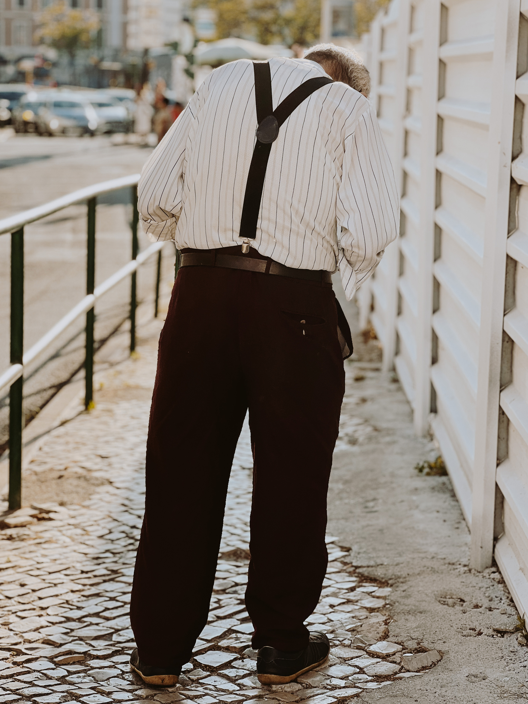An hunched man, wearing suspenders. 