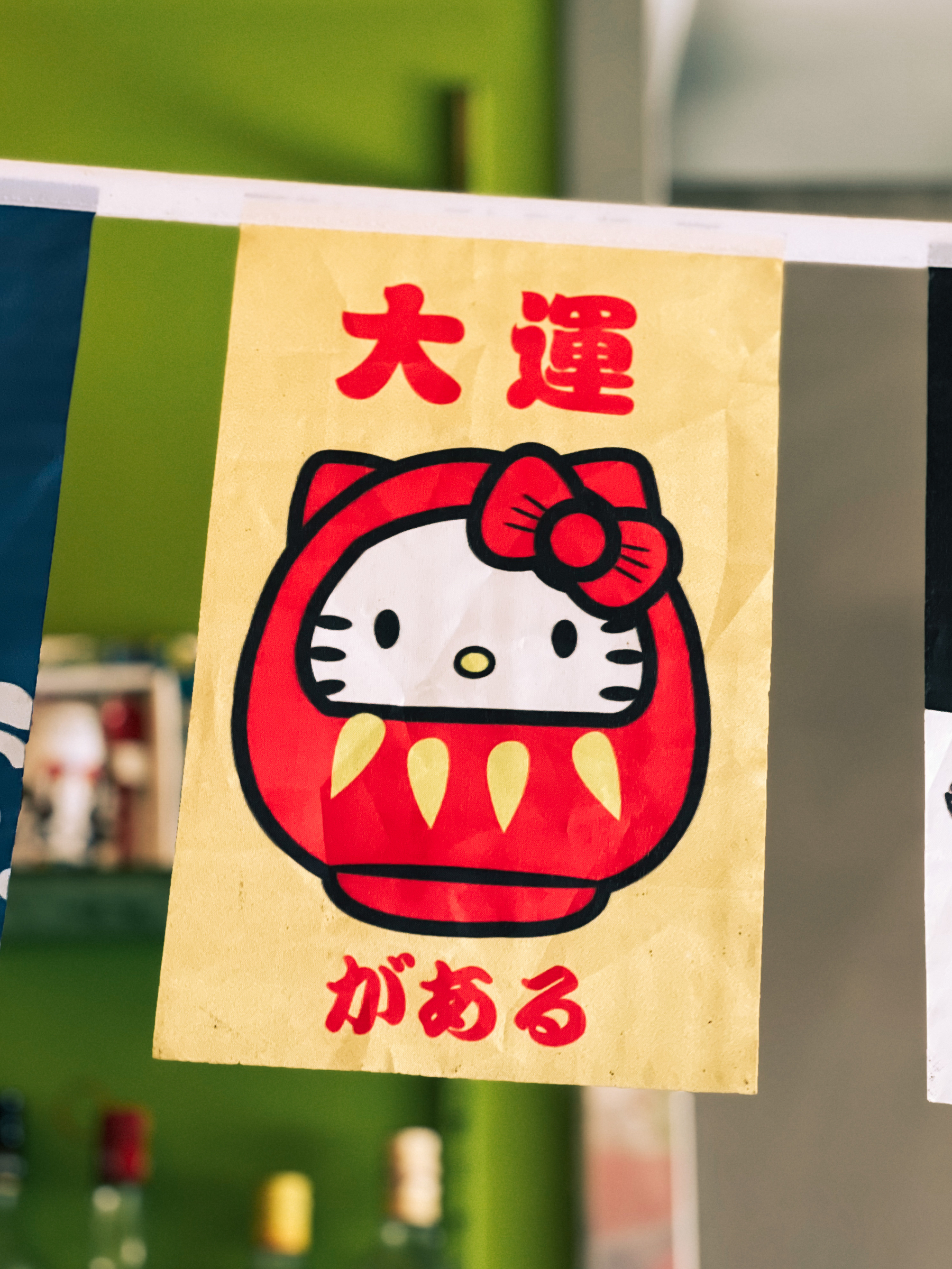 A Japanese restaurant banner, with Hello Kitty as a Daruma doll, and the words 大運.