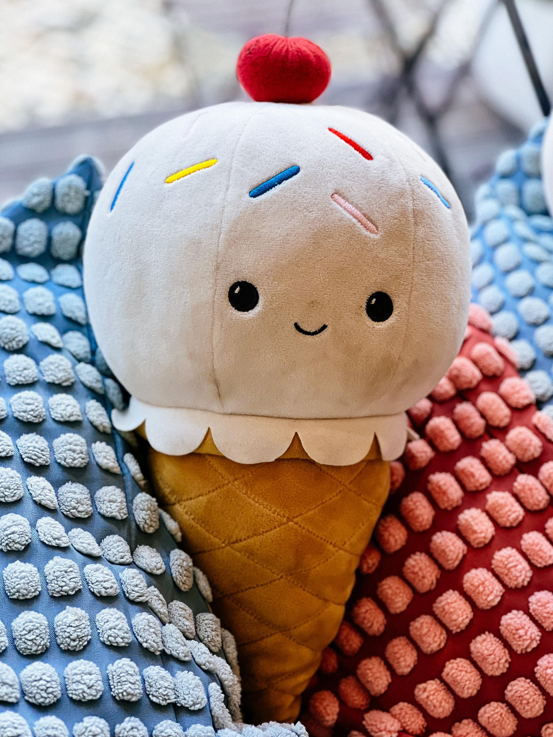 a plush ice-cream cone, surrounded by fluffy pillows