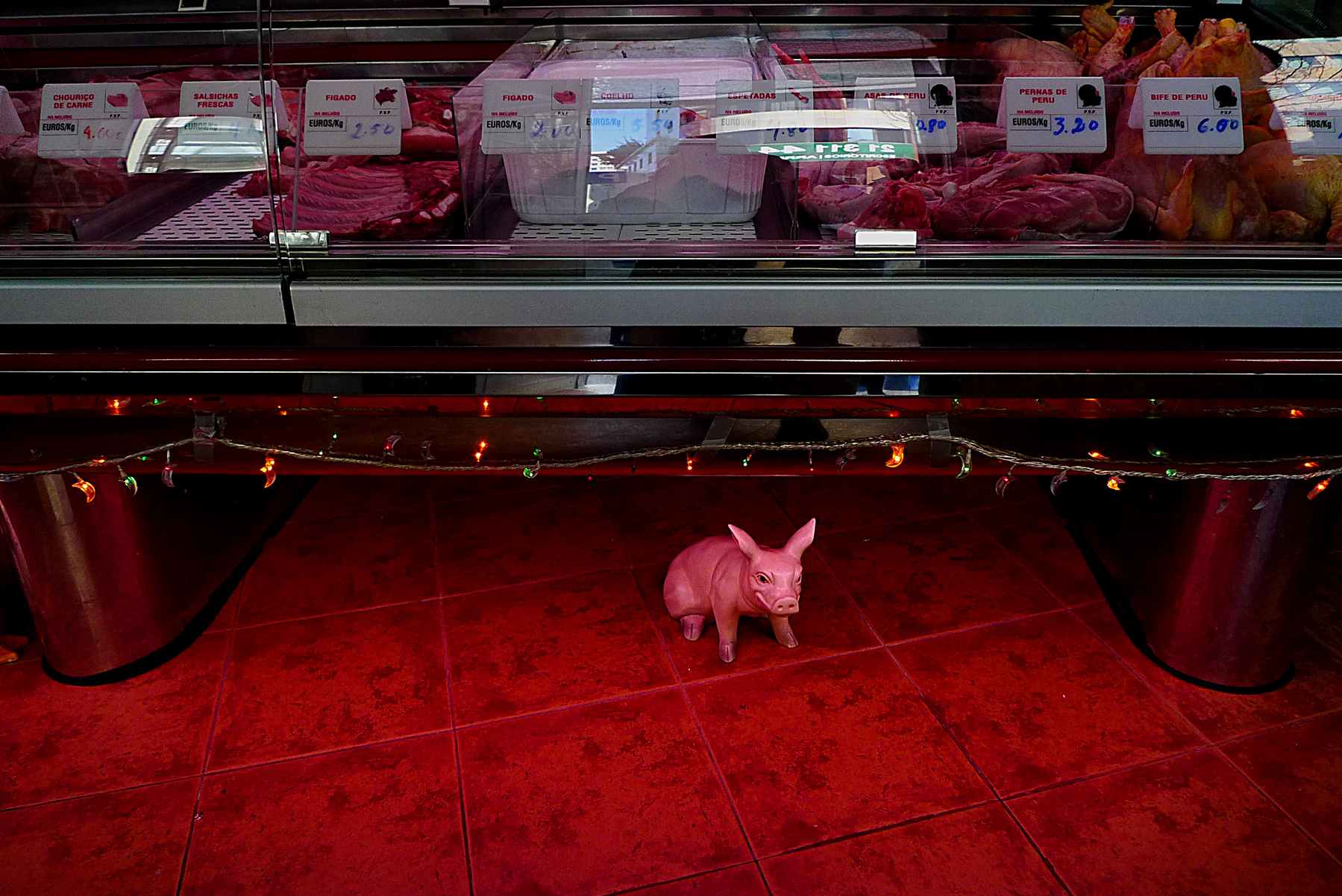 A ceramic pig on a red butcher floor.