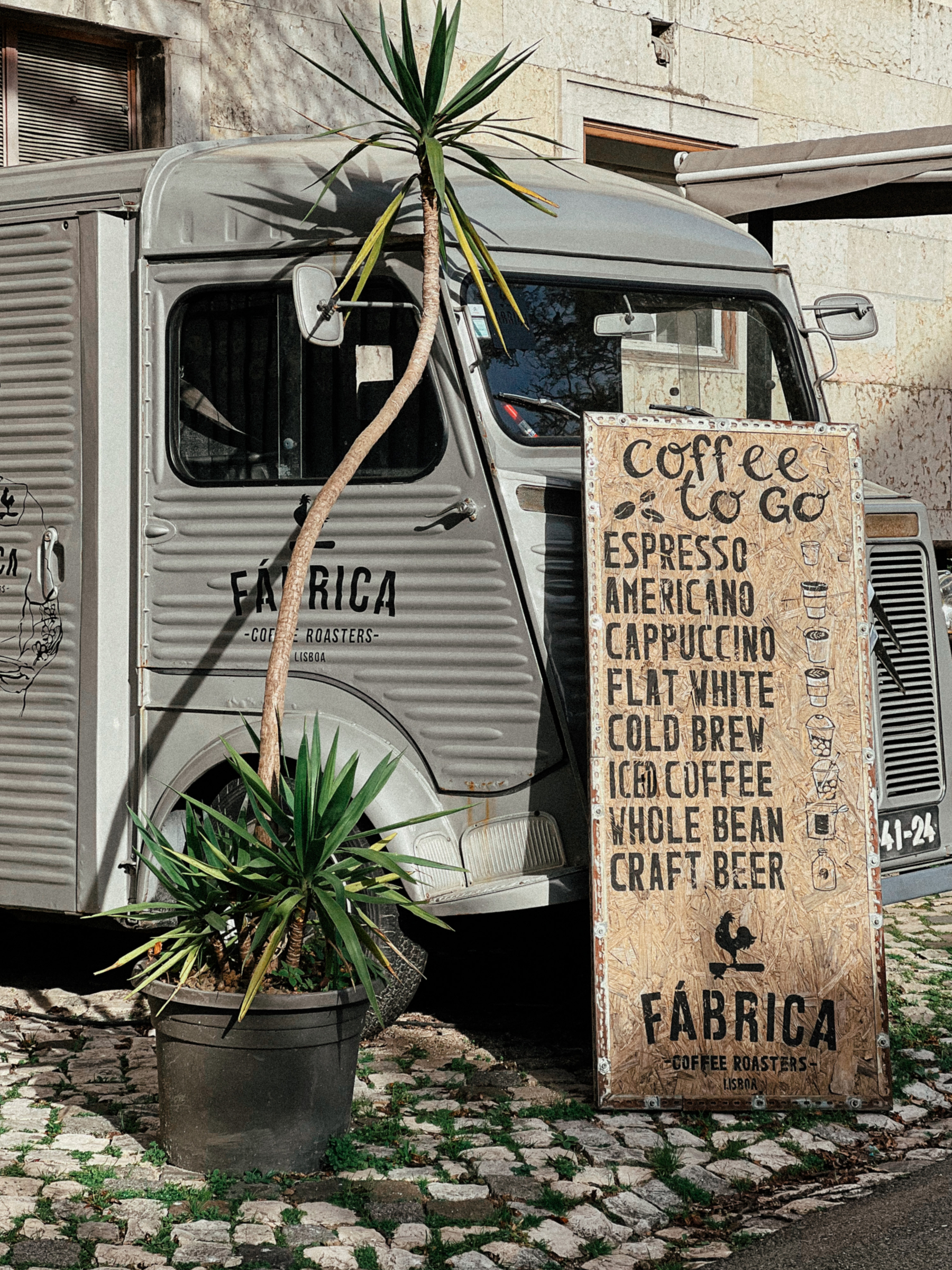 A coffee truck, with a small potted palm by the side. 