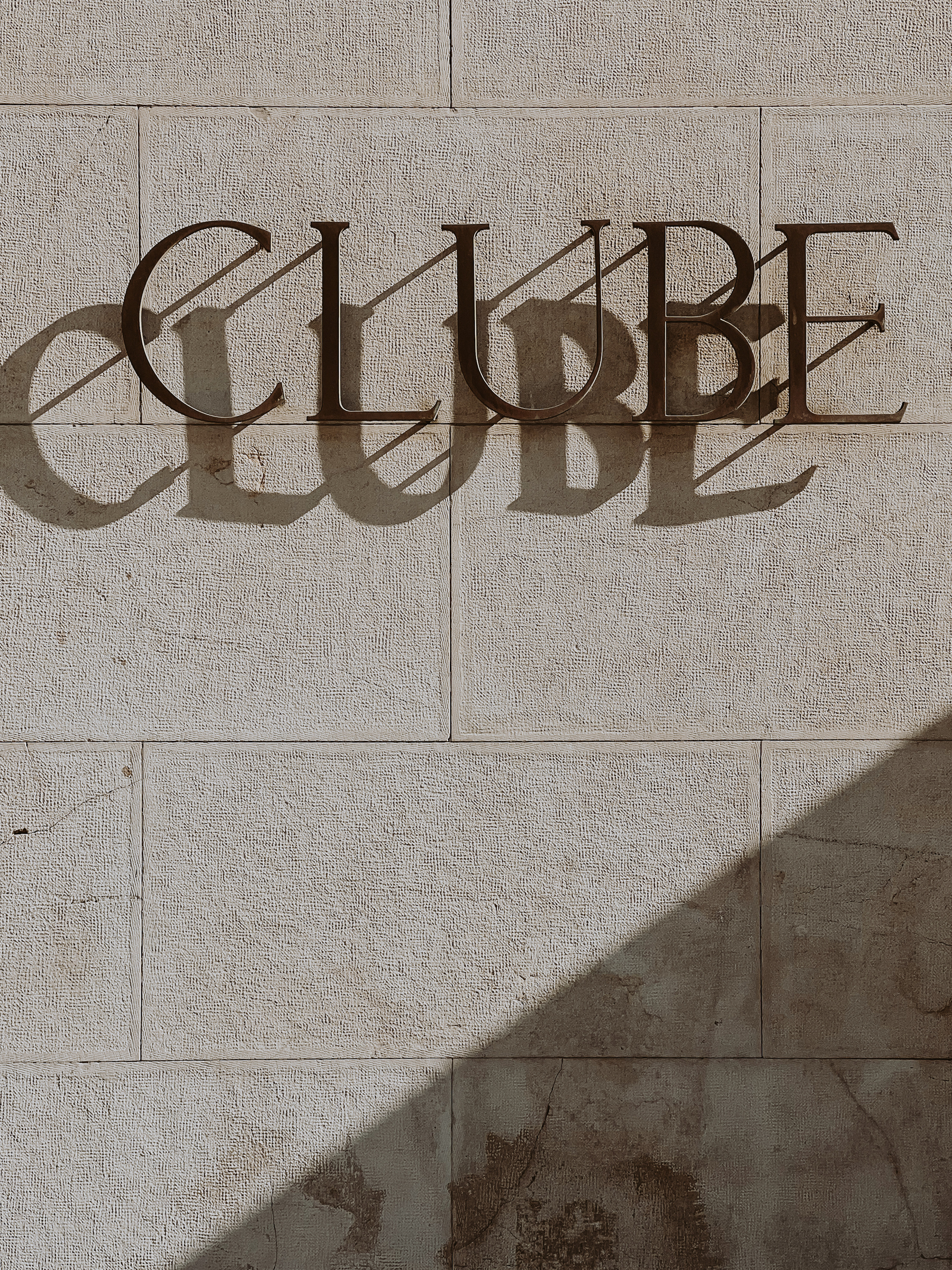 The word “Clube”, on a wall, with a drop shadow effect. 