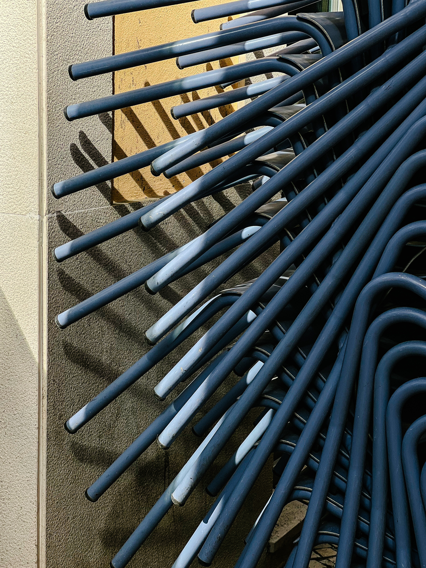 A bunch of chairs, stacked up against a wall. 