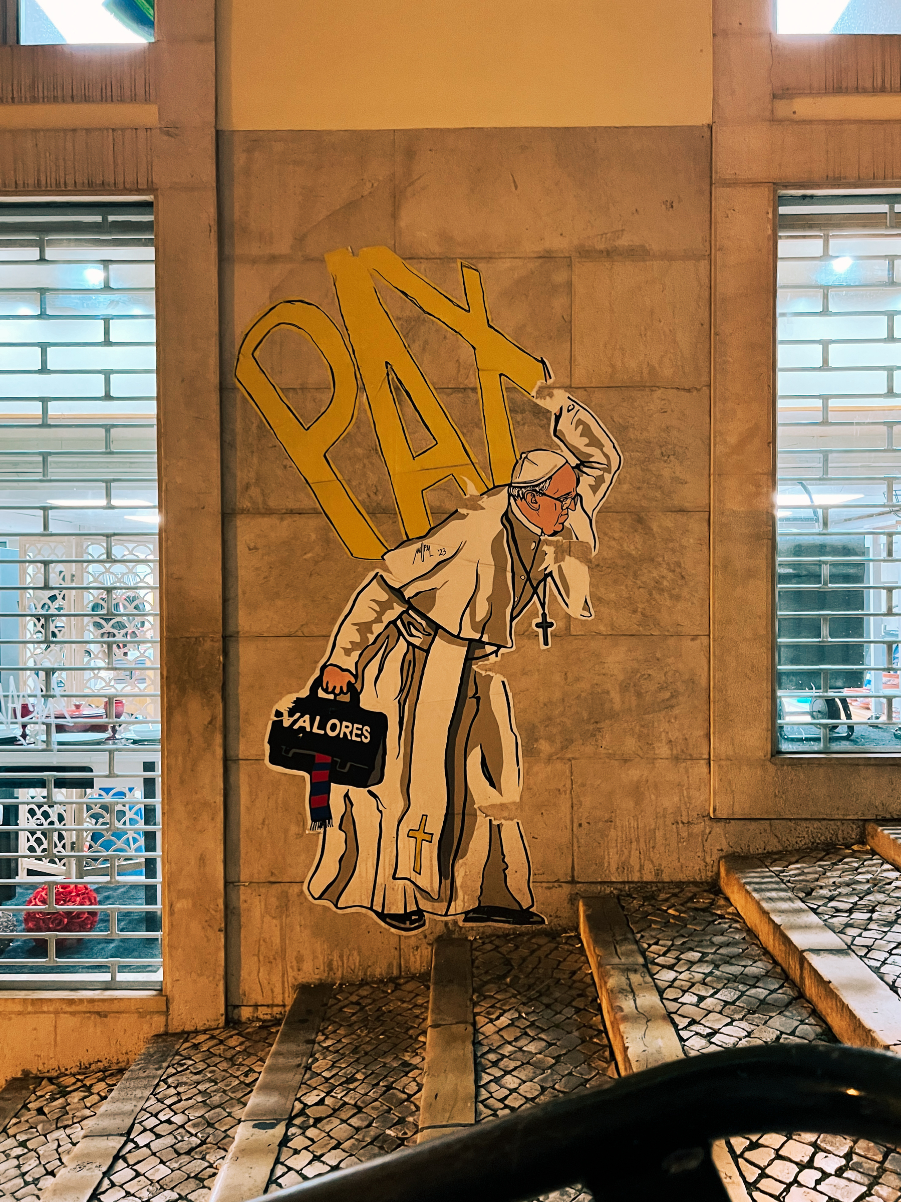 A life sized drawing of the pope carrying the word “PAX” on his back, and a bag with “valores” on one hand. 