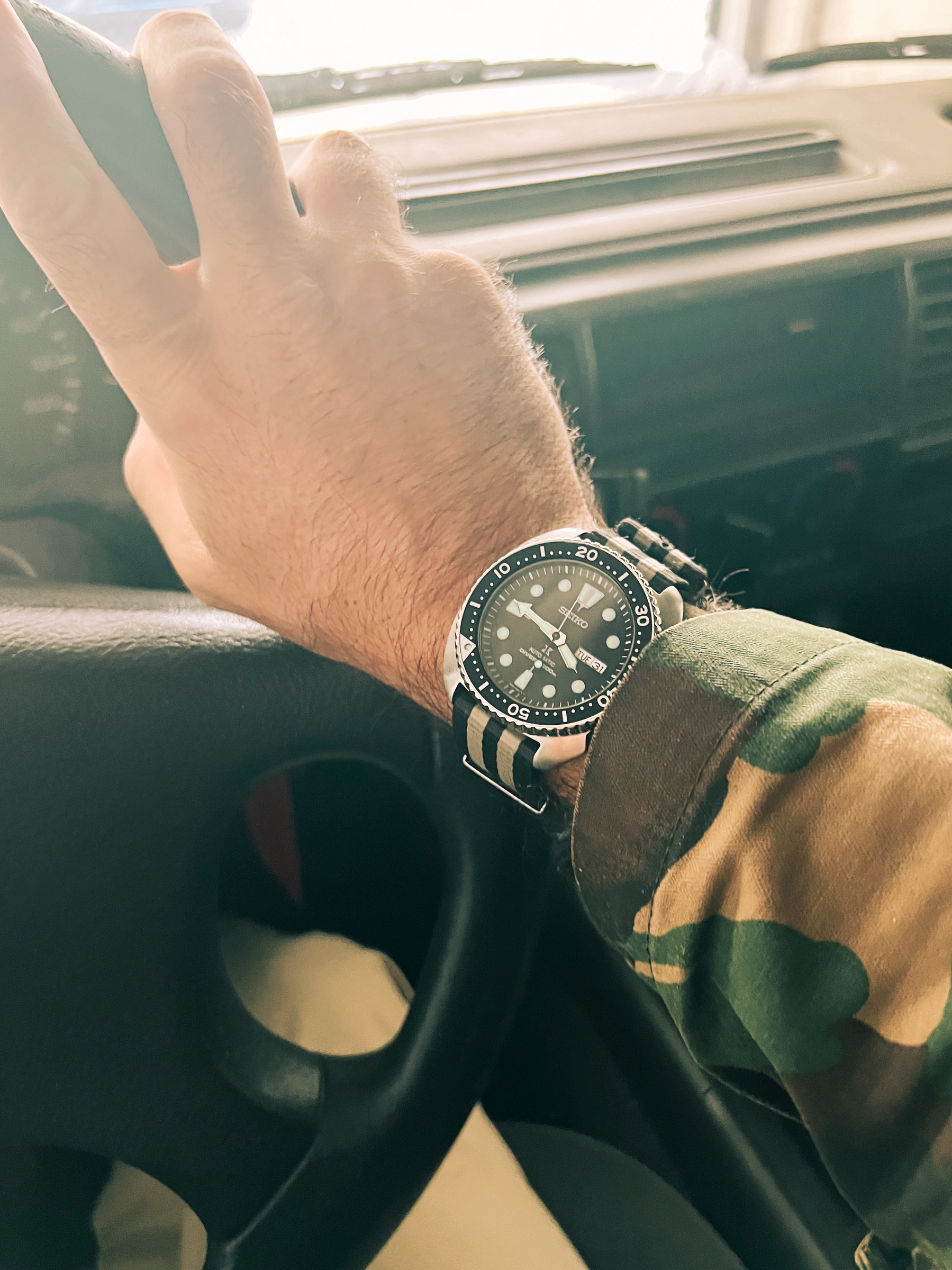 A Seiko Turtle on a wrist. Inside a car. 