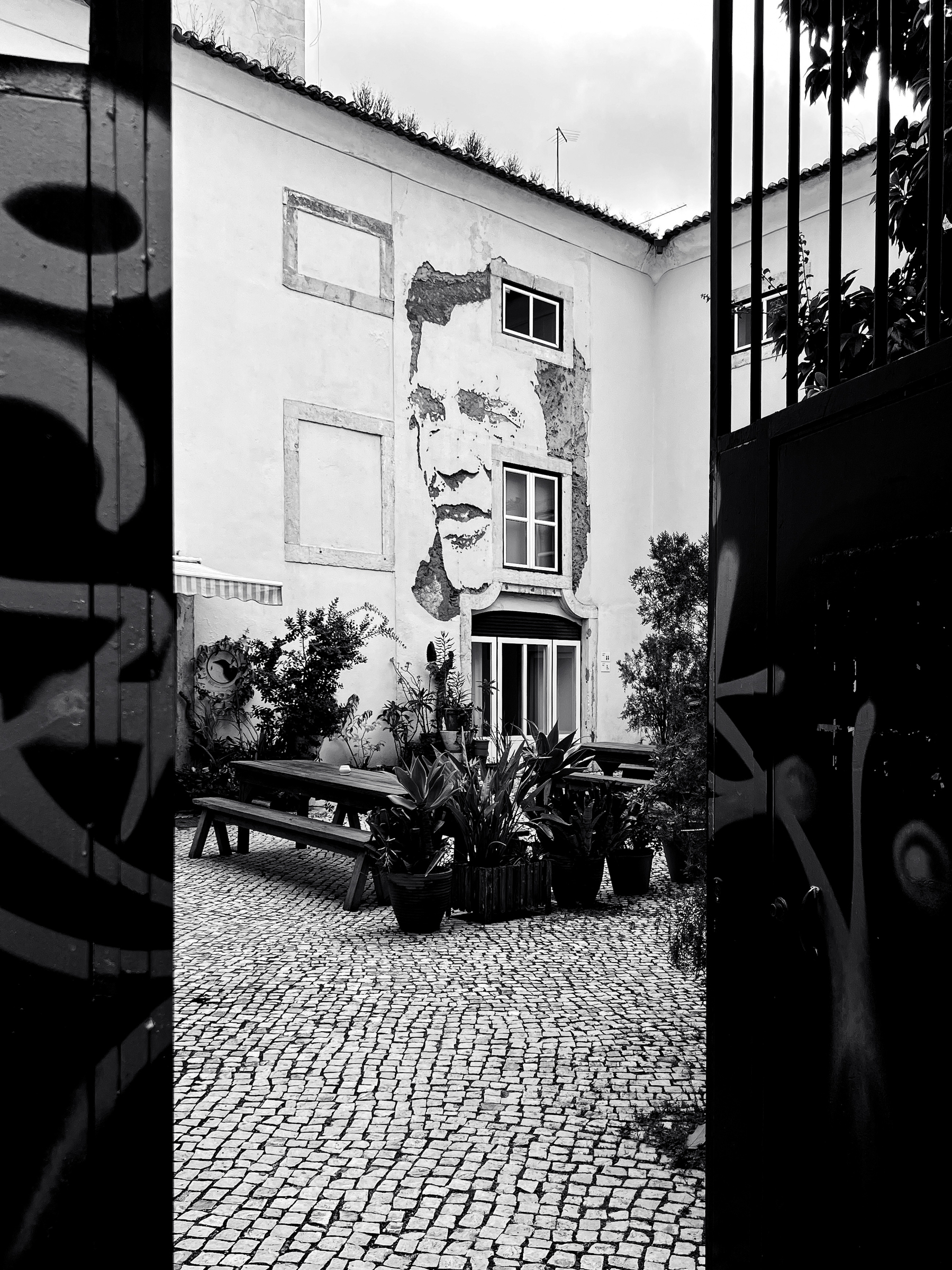 Black and white photo, Vhils artwork on a patio. 