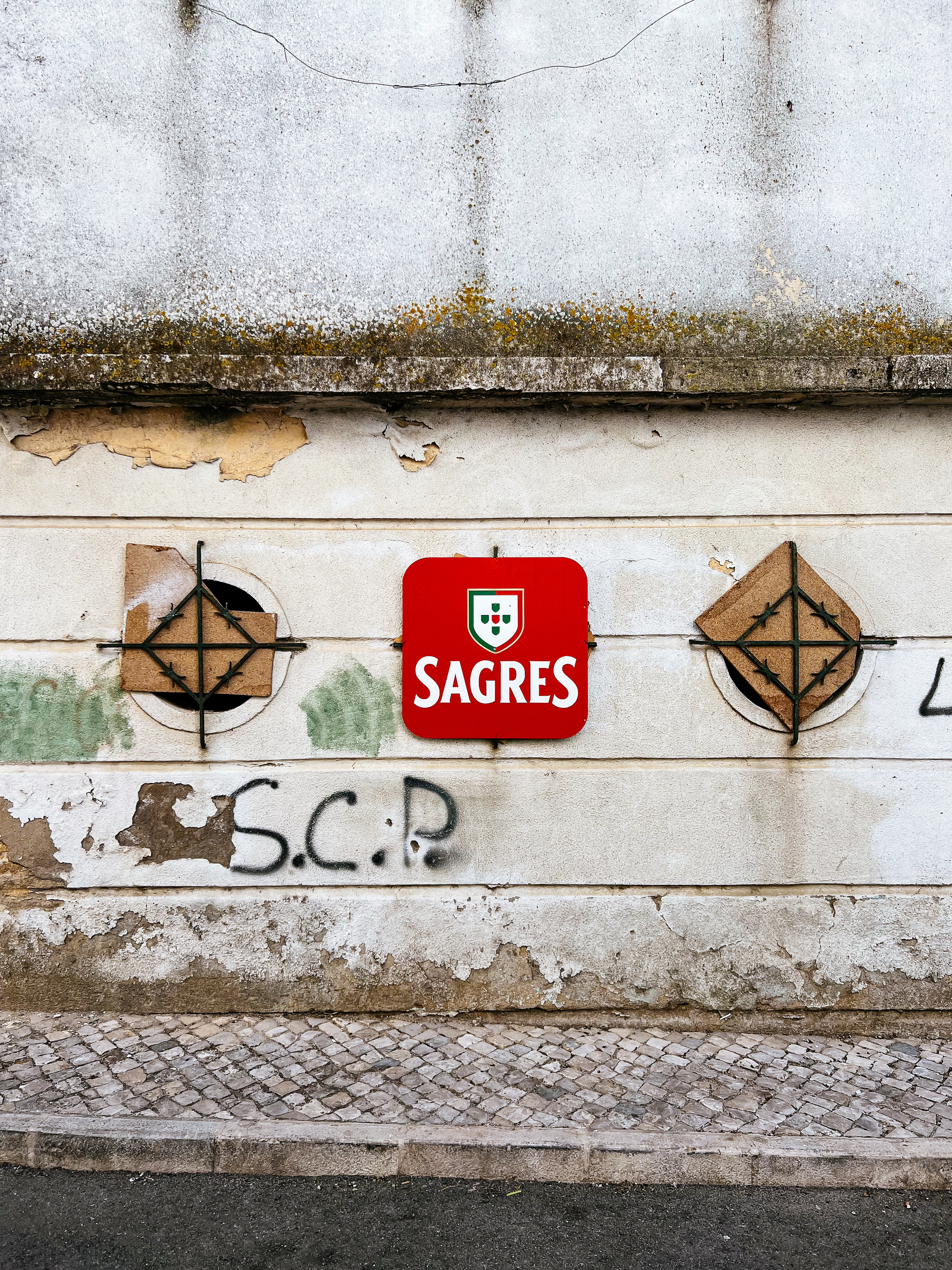 Side wall, two small windows, both covered. Ad for Sagres. 