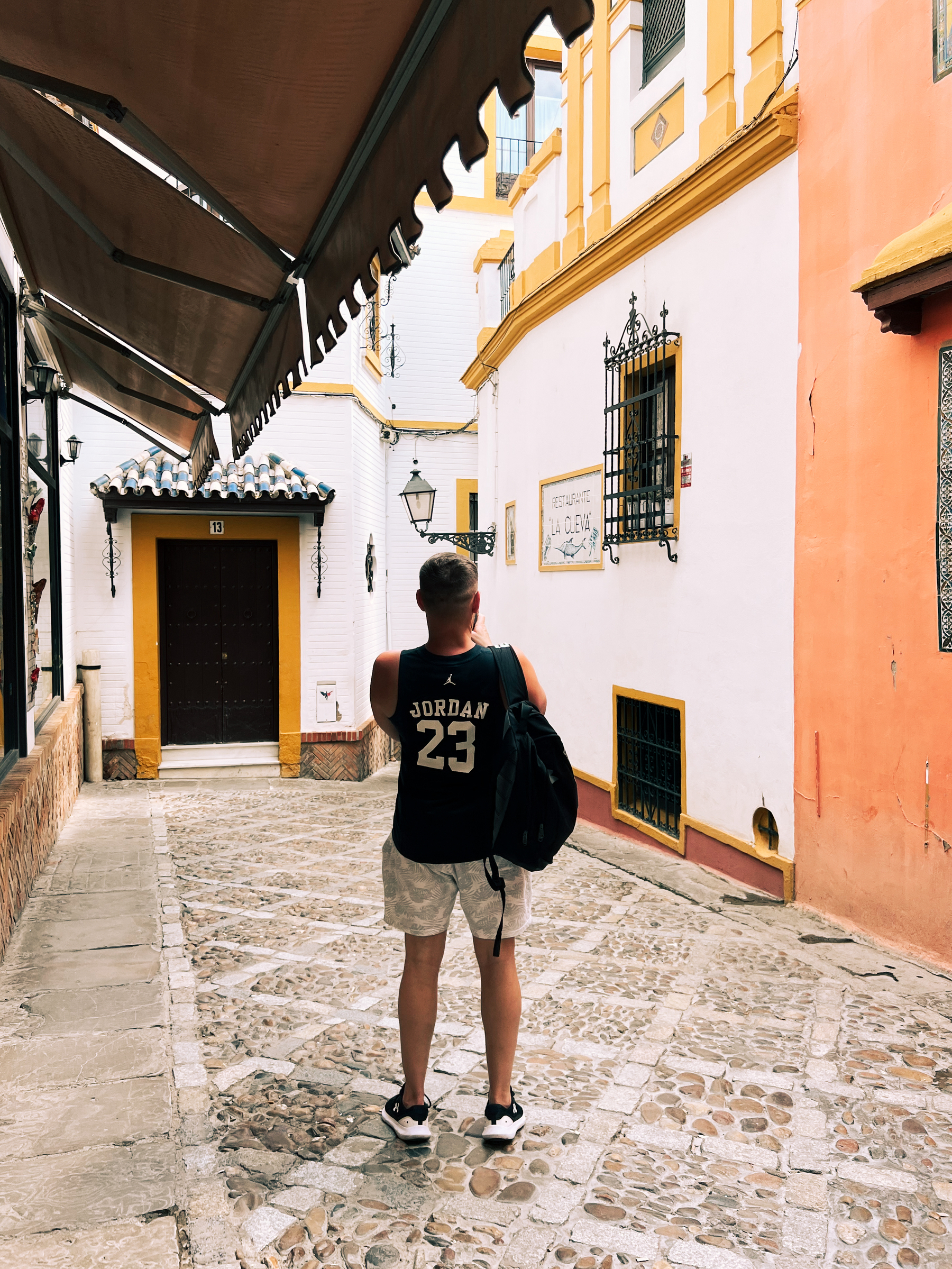 A tourist stops to take a photo in Santa Cruz, a classic neighborhood in Sevilla. Narrow streets and classic buildings. 