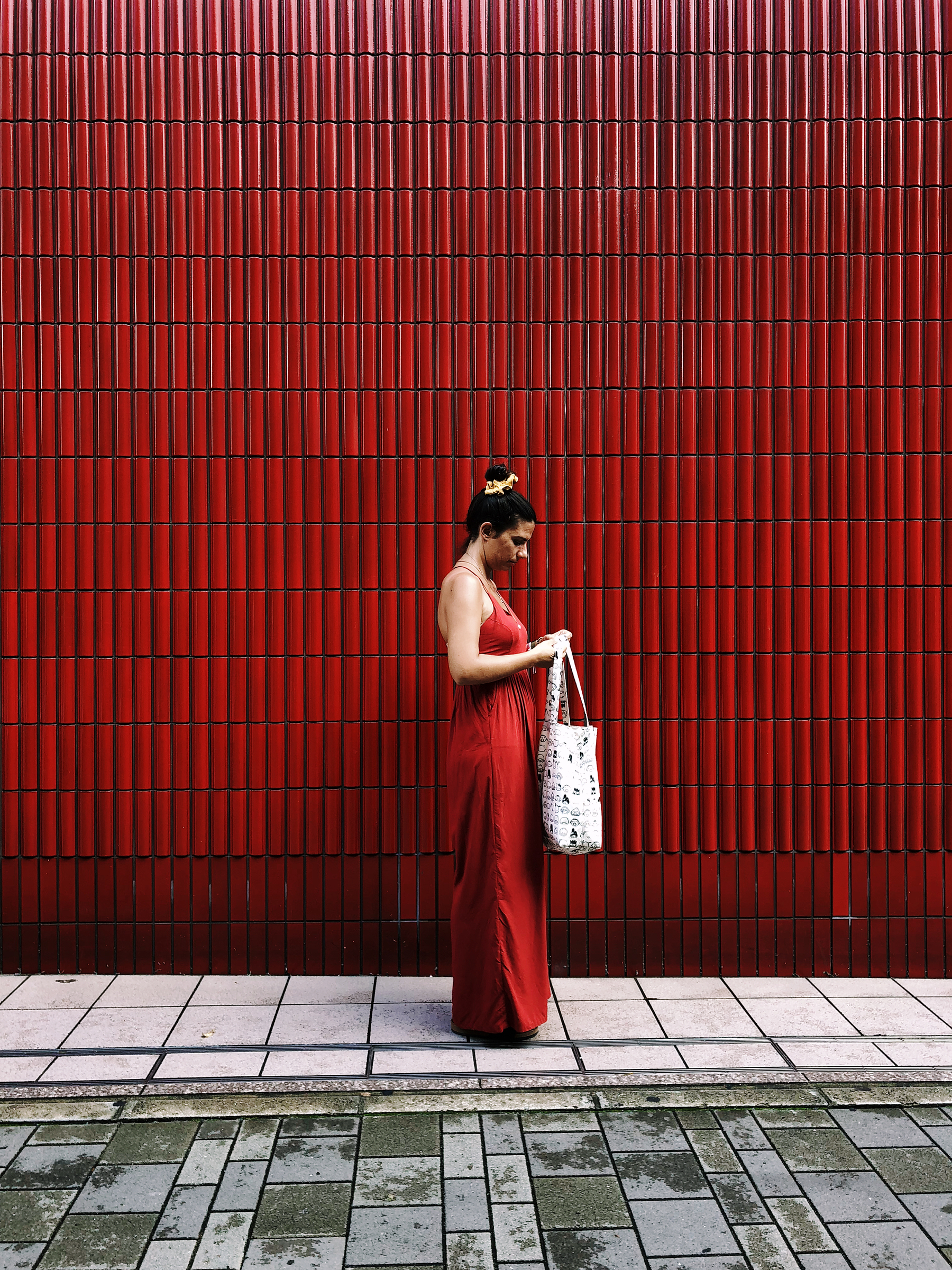A woman wearing a red dress, against a red wall.