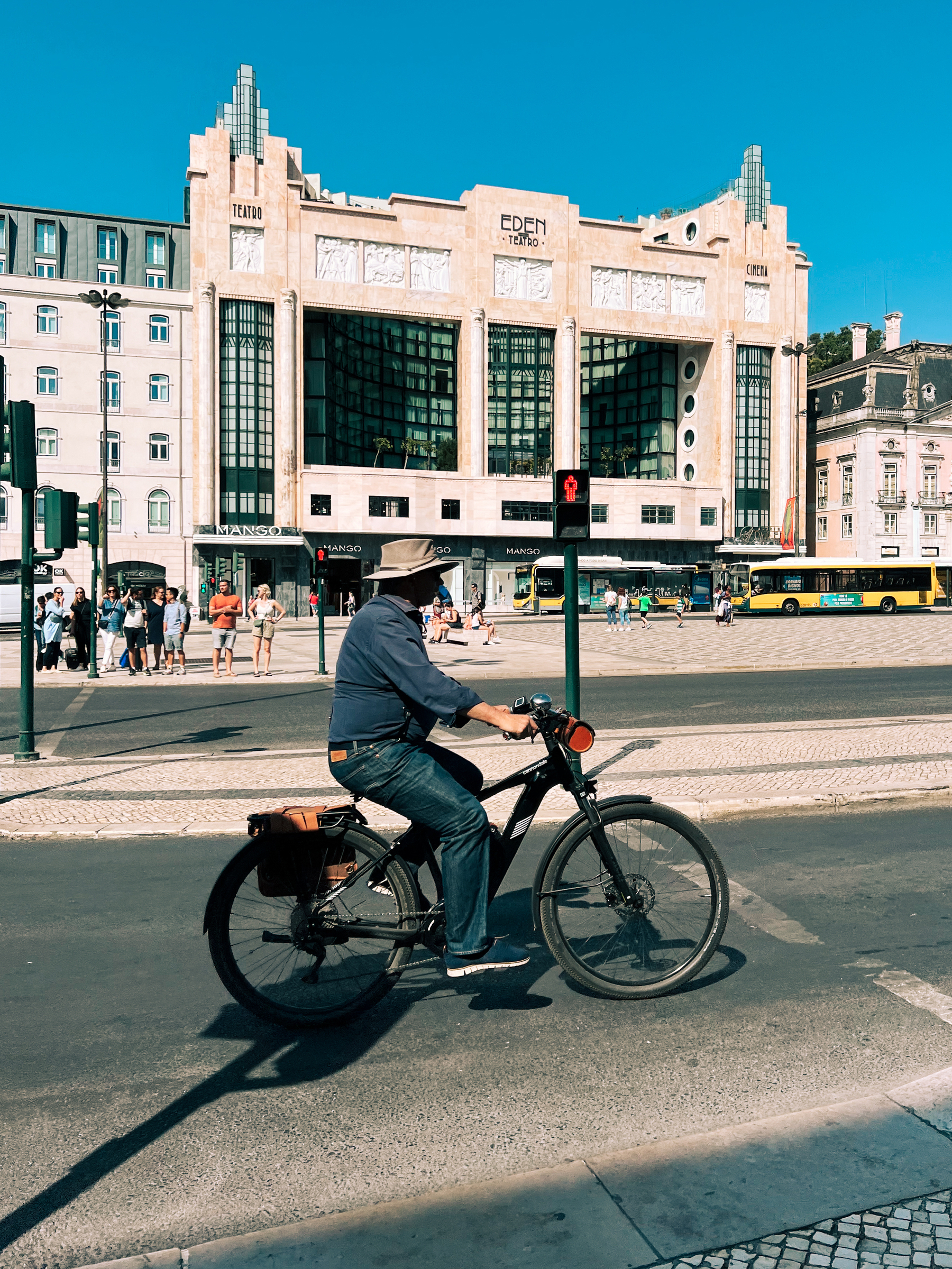 A man rides a bicycle, with a lovely building in the back. 