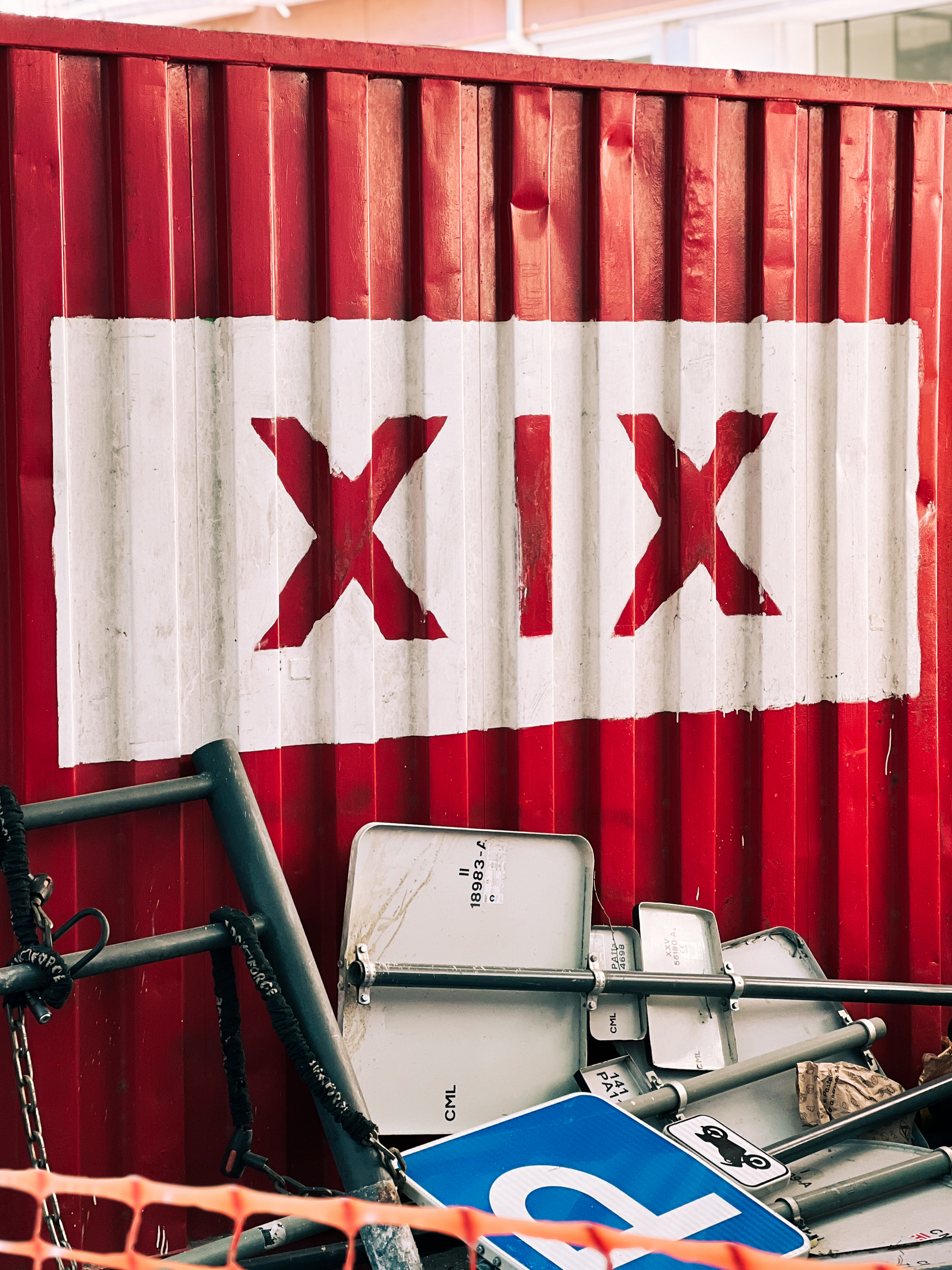 A red shipping container with “XIX” on the side, and some construction material buildup next to it.