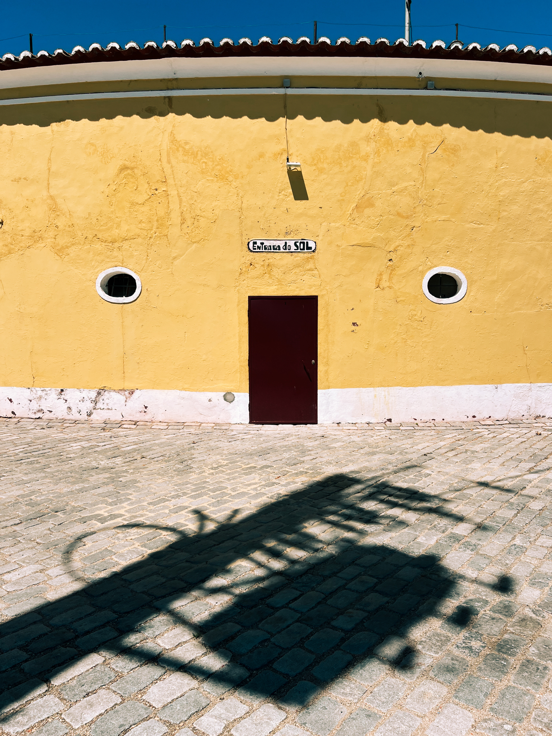Side entrance to a bullring, a door and two small, round, windows. Looks like a face. 