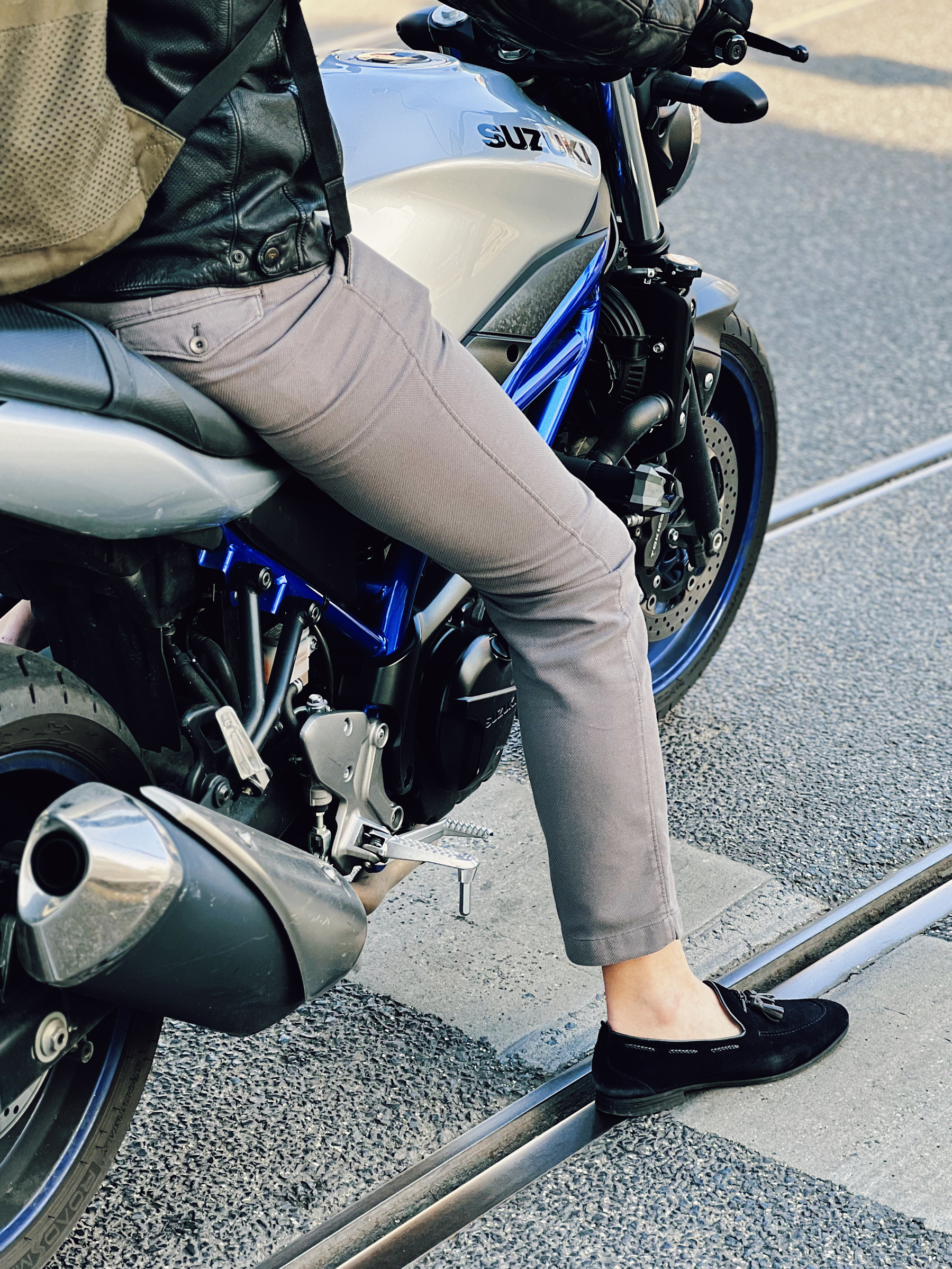 A man rides a motorcycle with suede shoes. 
